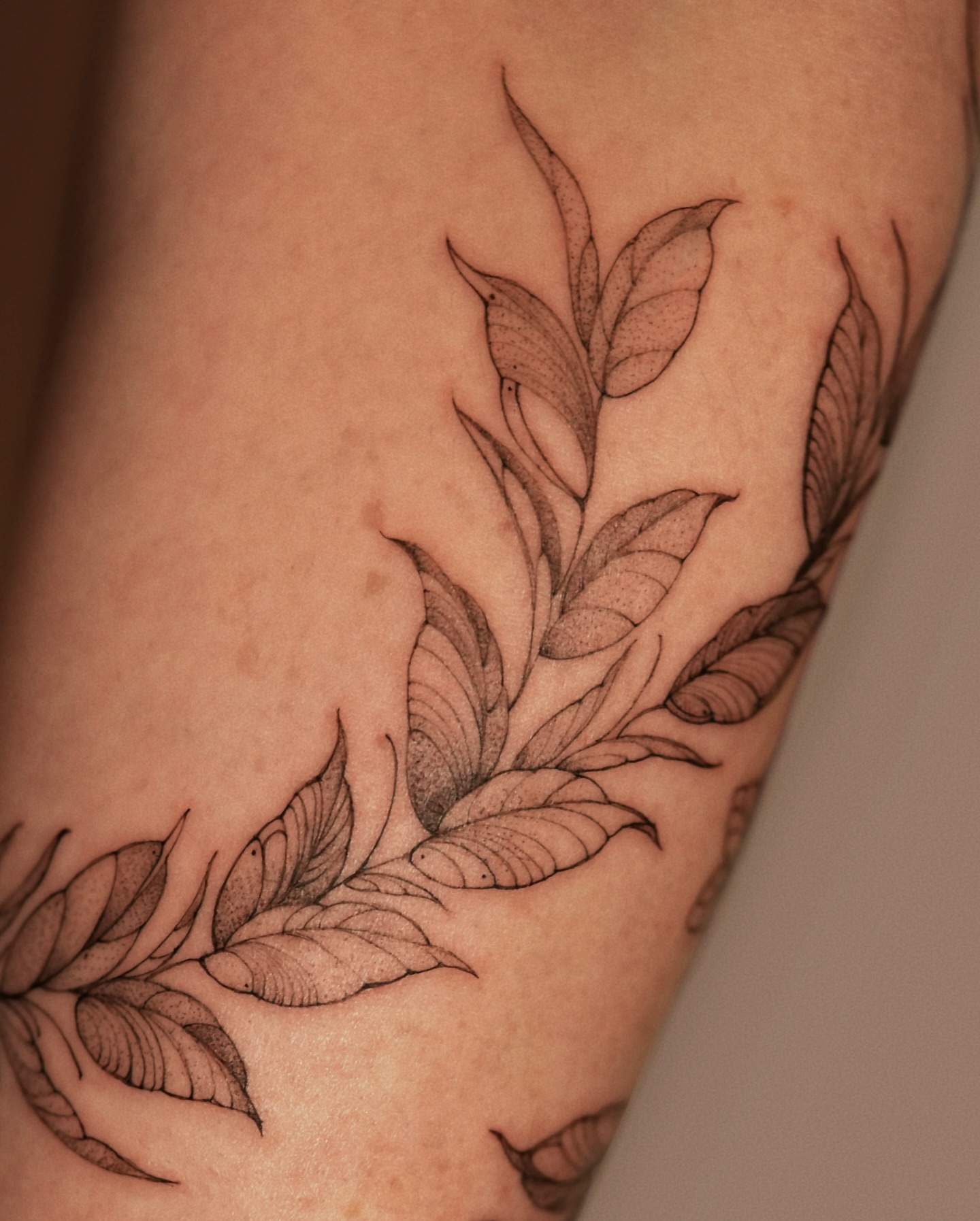 Leafy branch black and grey tattoo on the forearm by Zalina Loriia