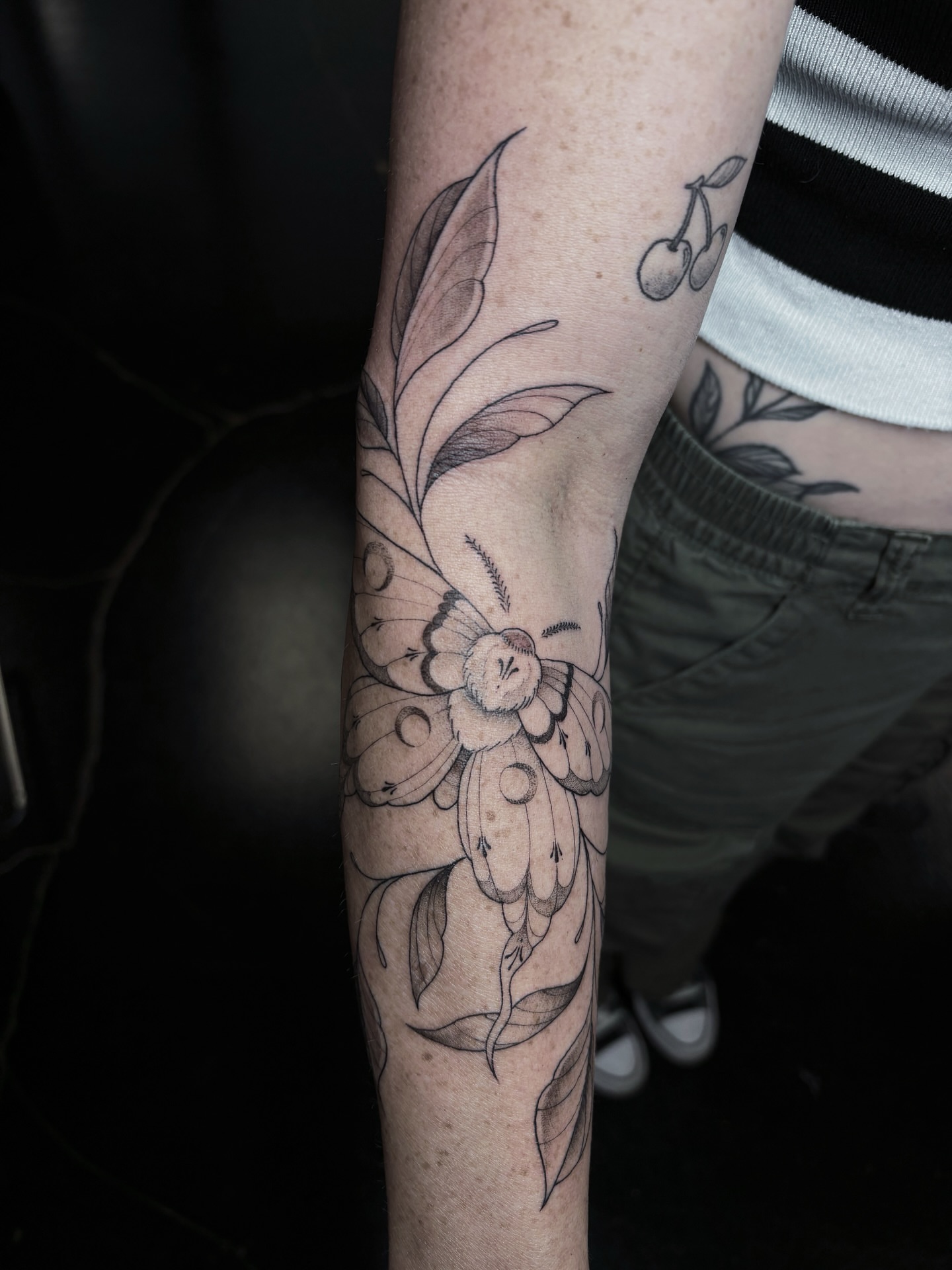 Flower and leaves black and grey tattoo on the forearm by Fine Line Tattoo Artist