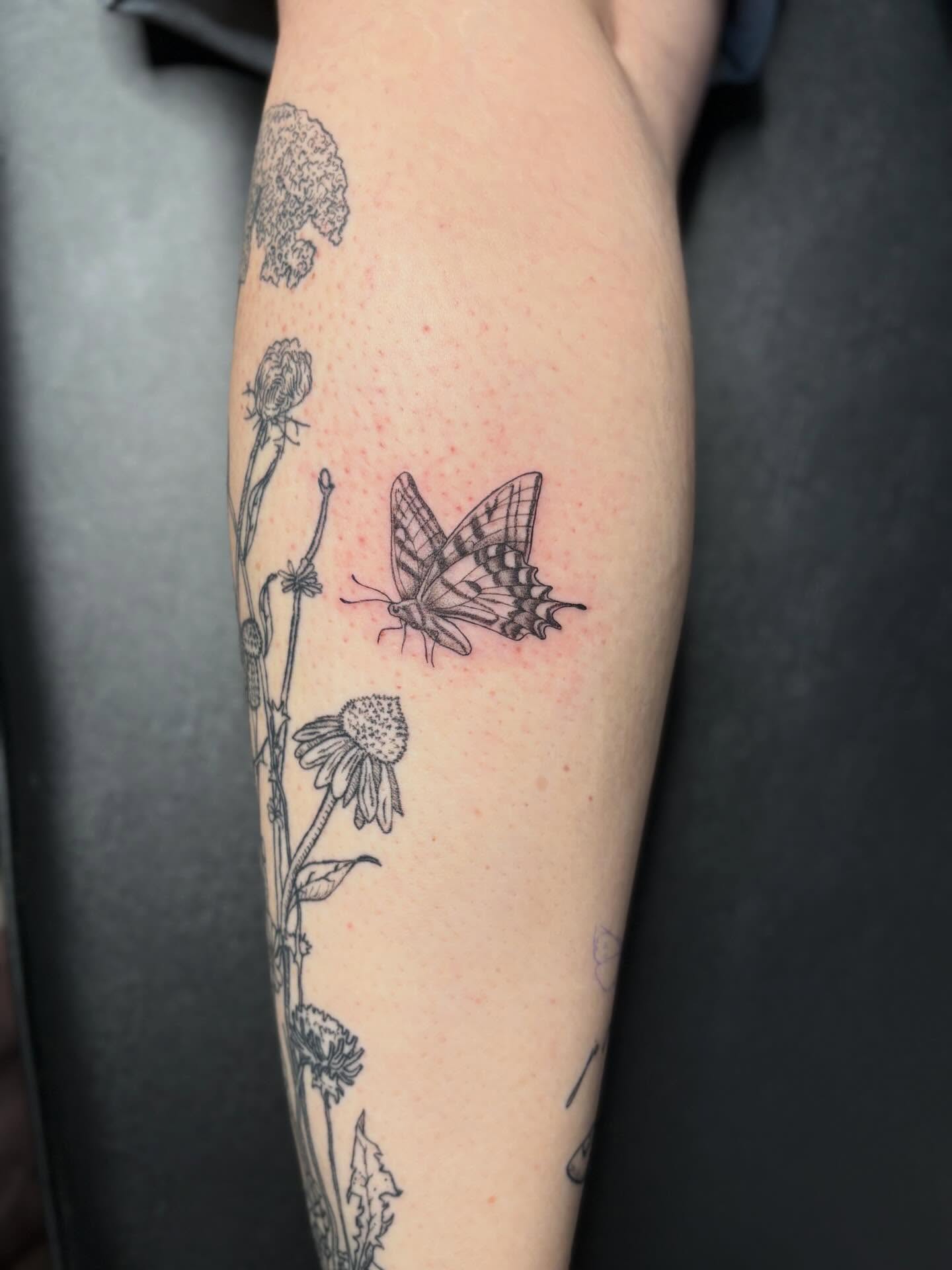 Butterfly and flowers black and grey tattoo on the forearm by Tessa Simmons - Tattoo Artist