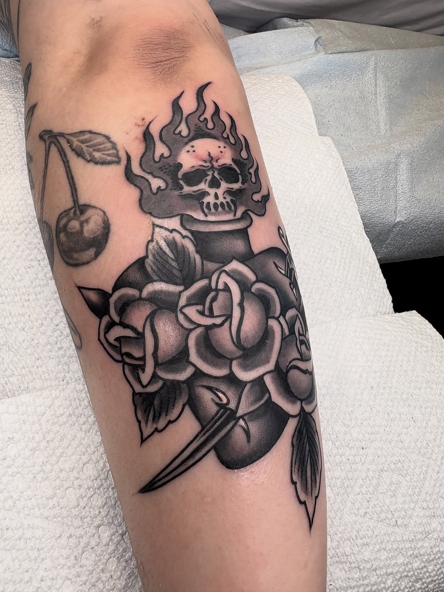 Flame, skull, roses, dagger, cherries American traditional tattoo on the forearm by Dallas Tattoo Artist