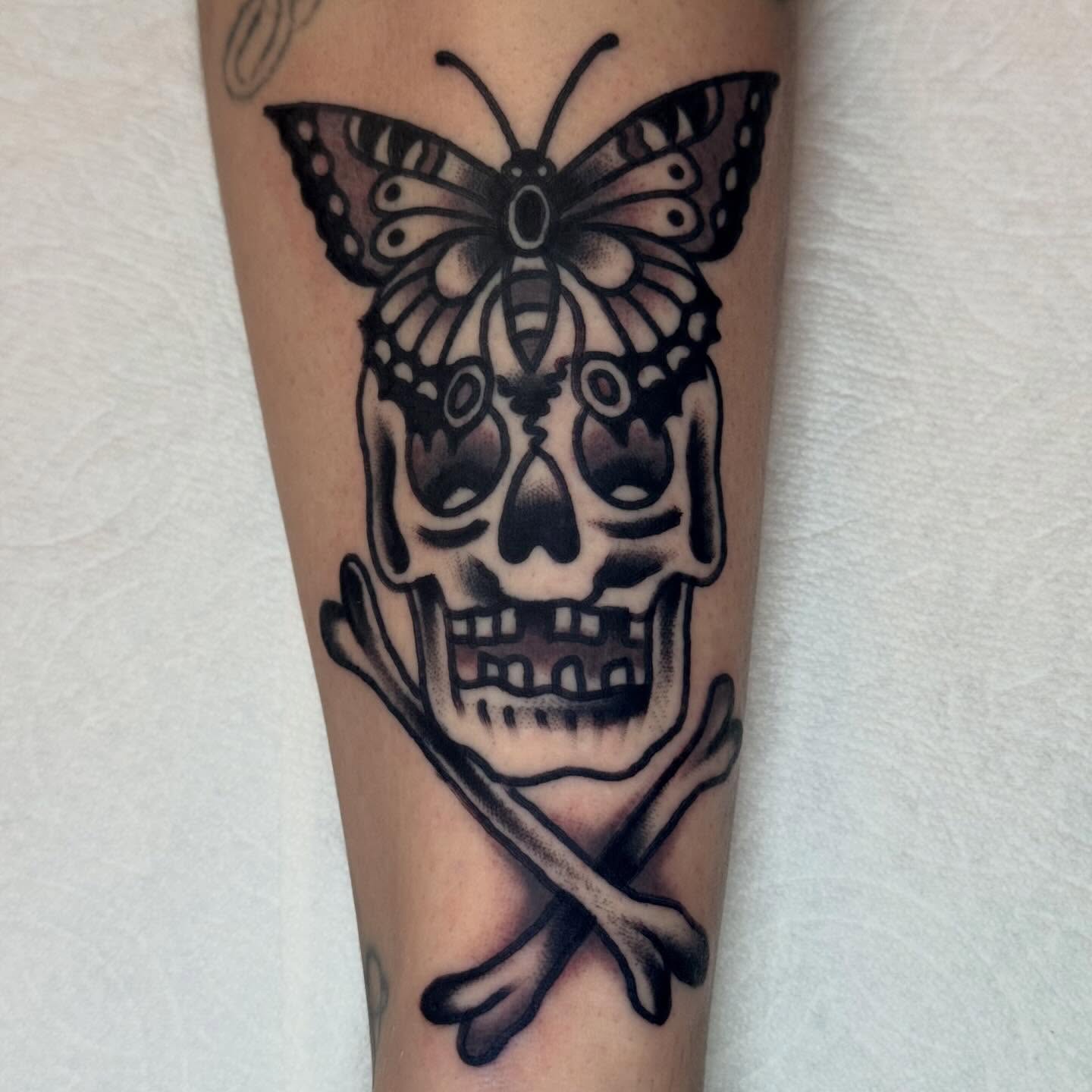 Skull and butterfly black and grey tattoo on the forearm by Eli Bernal