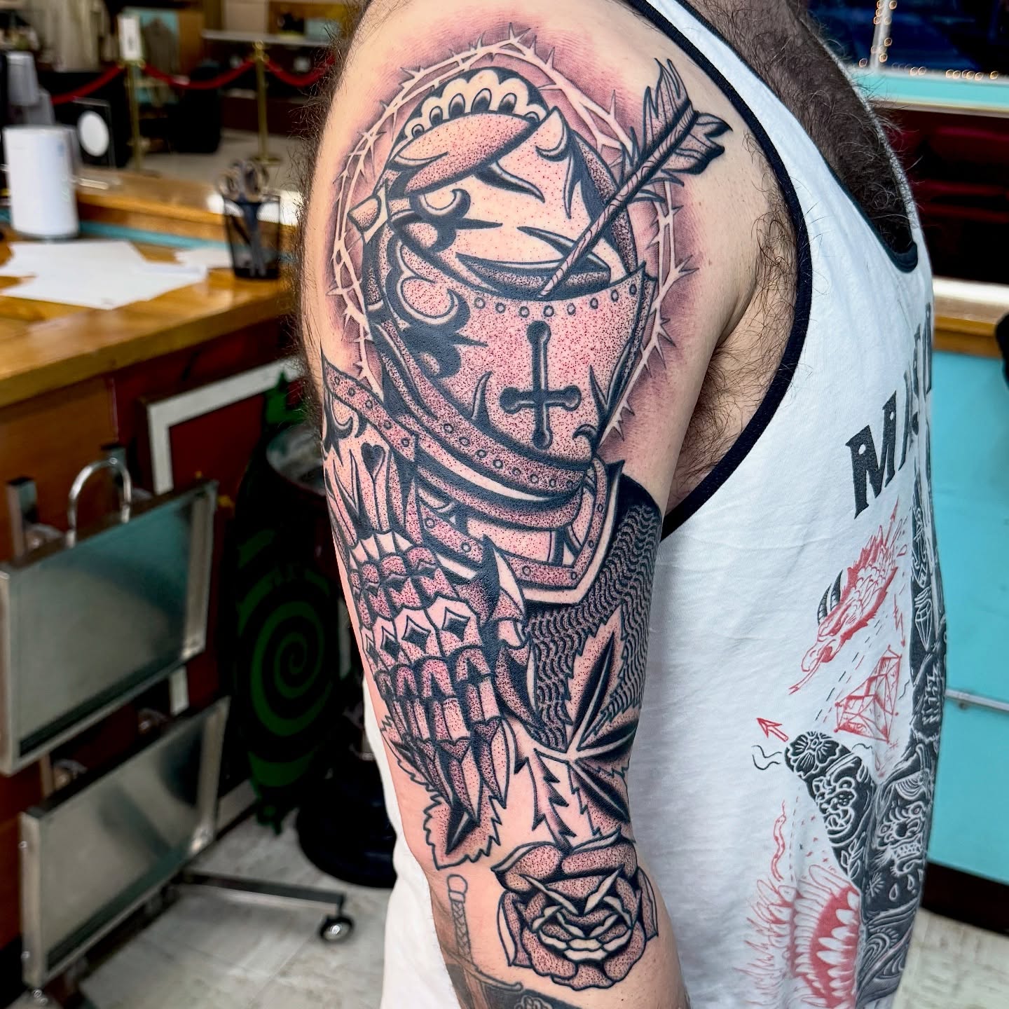 Knight helmet with cross dotwork tattoo on the shoulder by Sam
