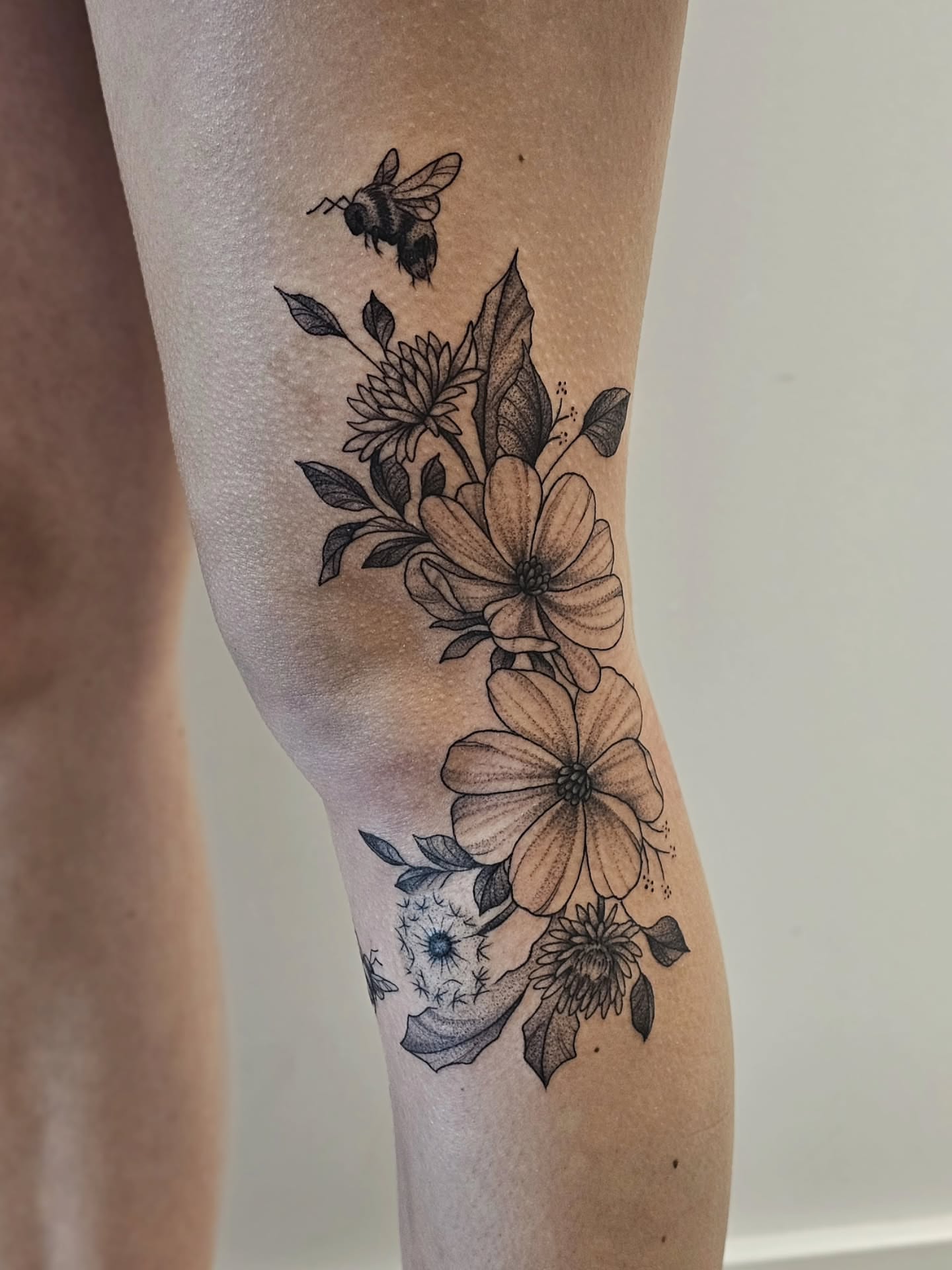 Flowers and bee black and grey tattoo on the forearm by Kylie Lund