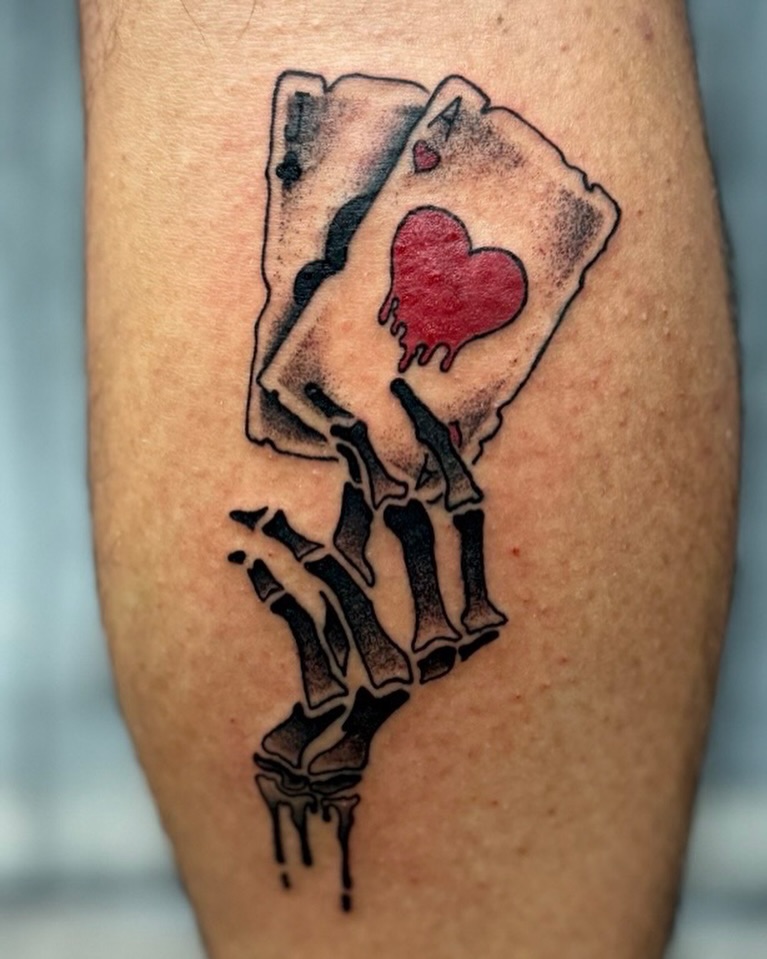 Playing card with bleeding heart black and grey tattoo on the forearm by David