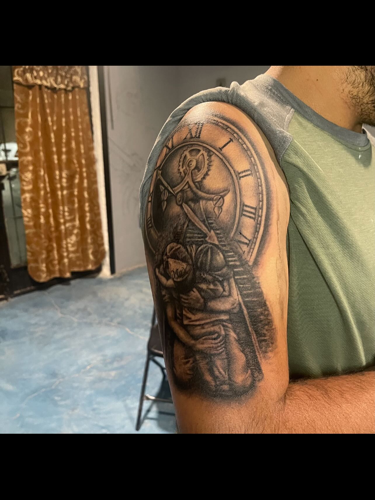 Clock and figure realism tattoo on the upper arm by Tu SanchoTattoos