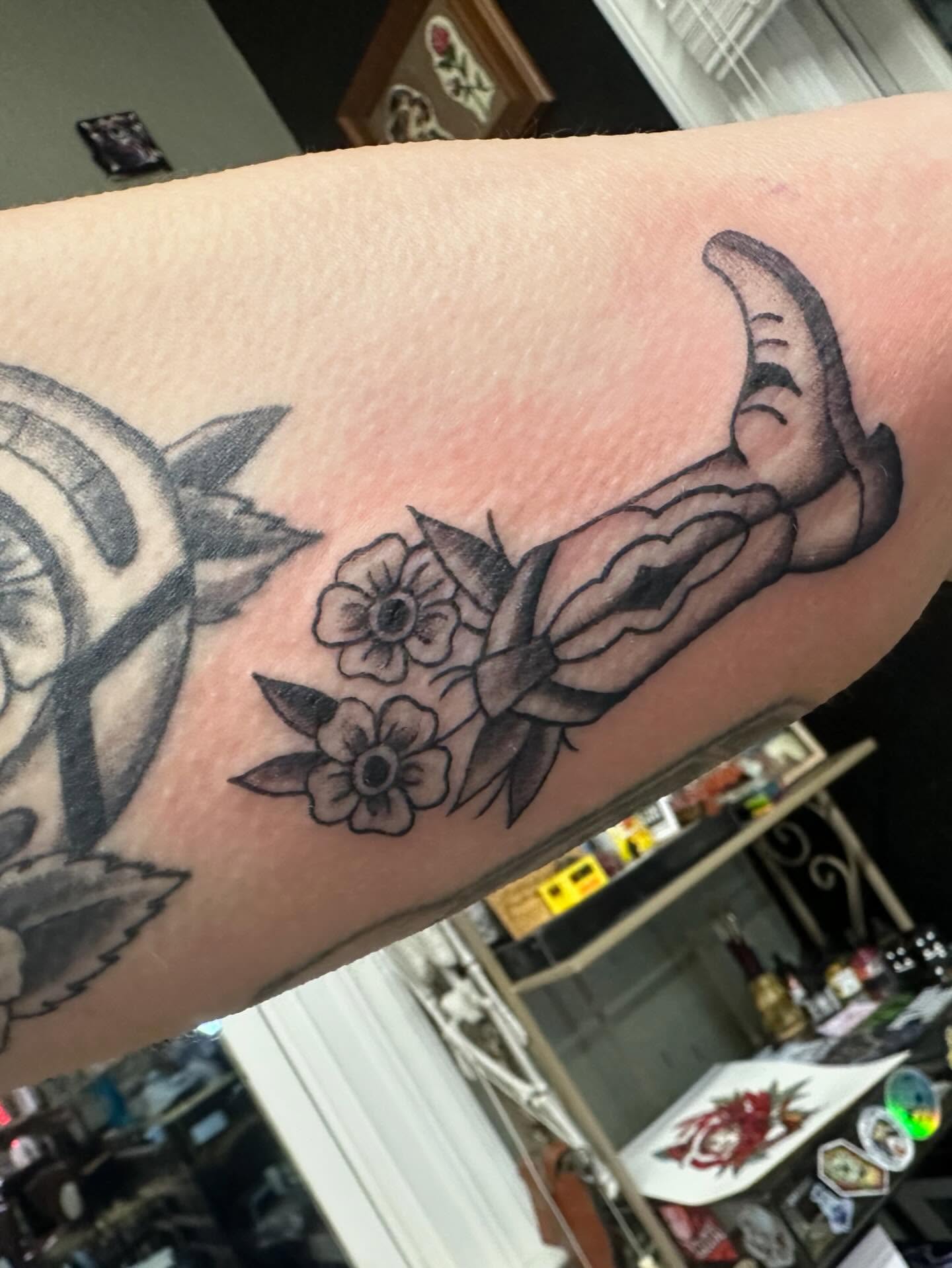 Cowboy boot and flowers American traditional tattoo on the forearm by Kaylee Woods