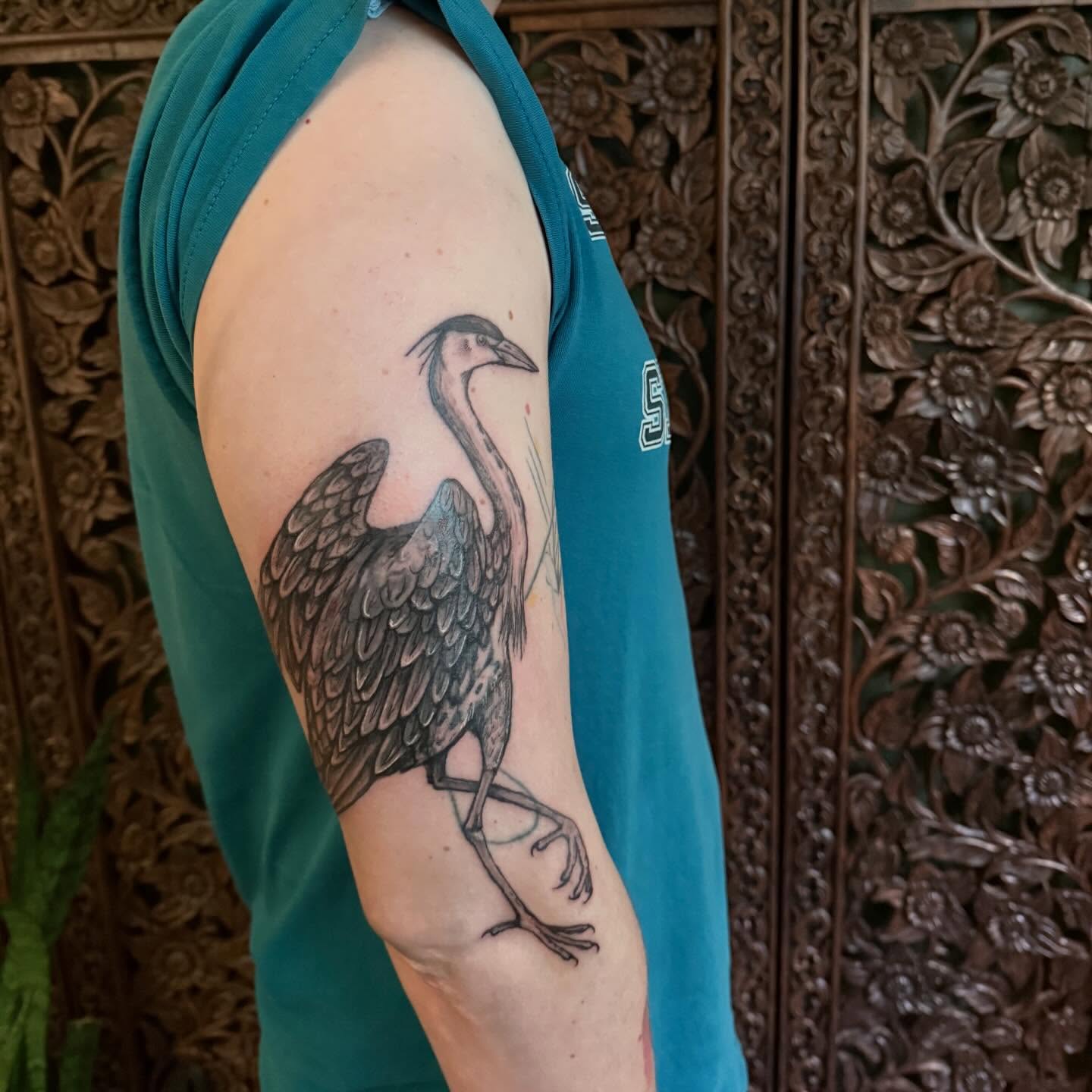 Heron black and grey tattoo on the upper arm by Emily Rose Lumsdaine