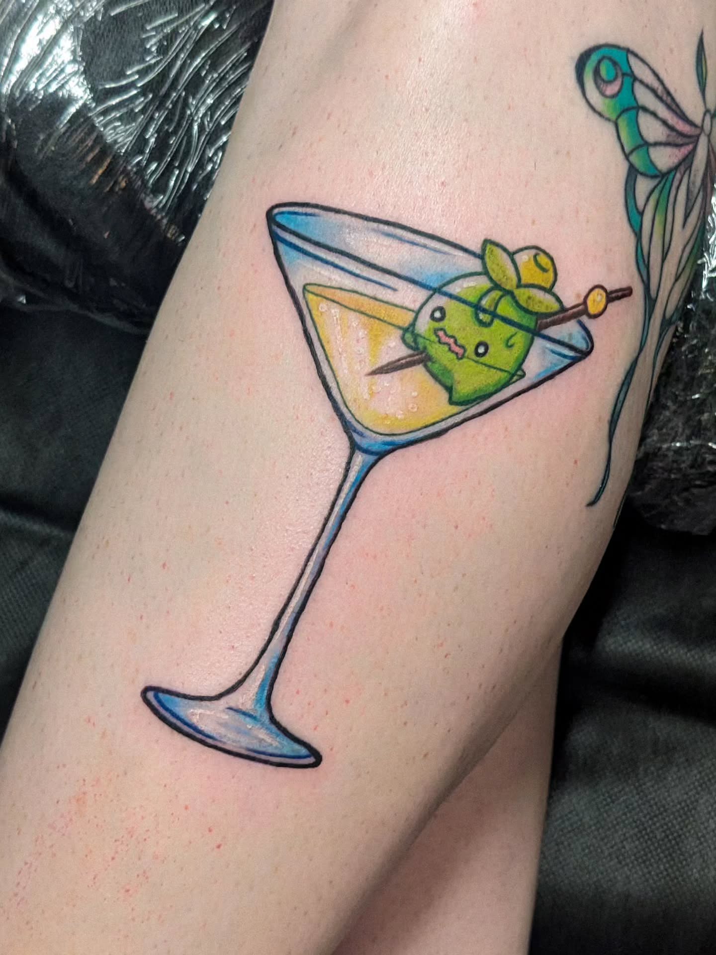 Martini glass with character illustrative tattoo on the forearm by robin ✨ portland tattoo artist