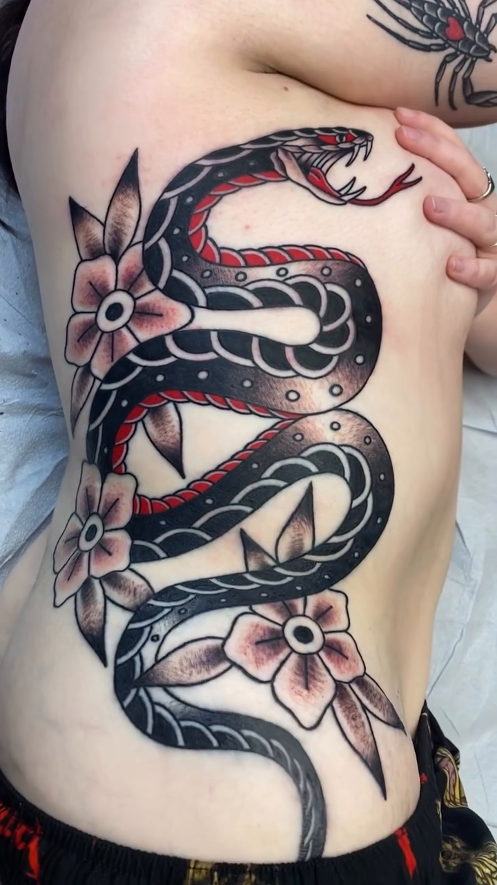 Snake and flowers American traditional tattoo on the ribs by Dice Lyon