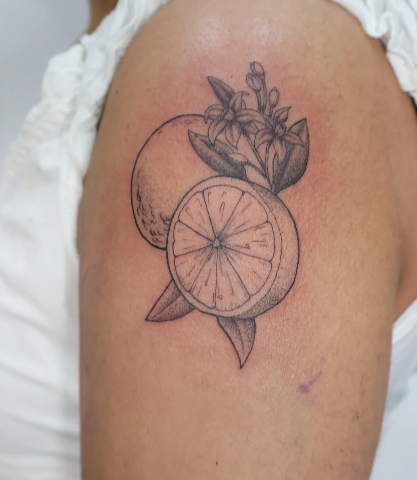 Orange slices black and grey tattoo on the shoulder by Joc