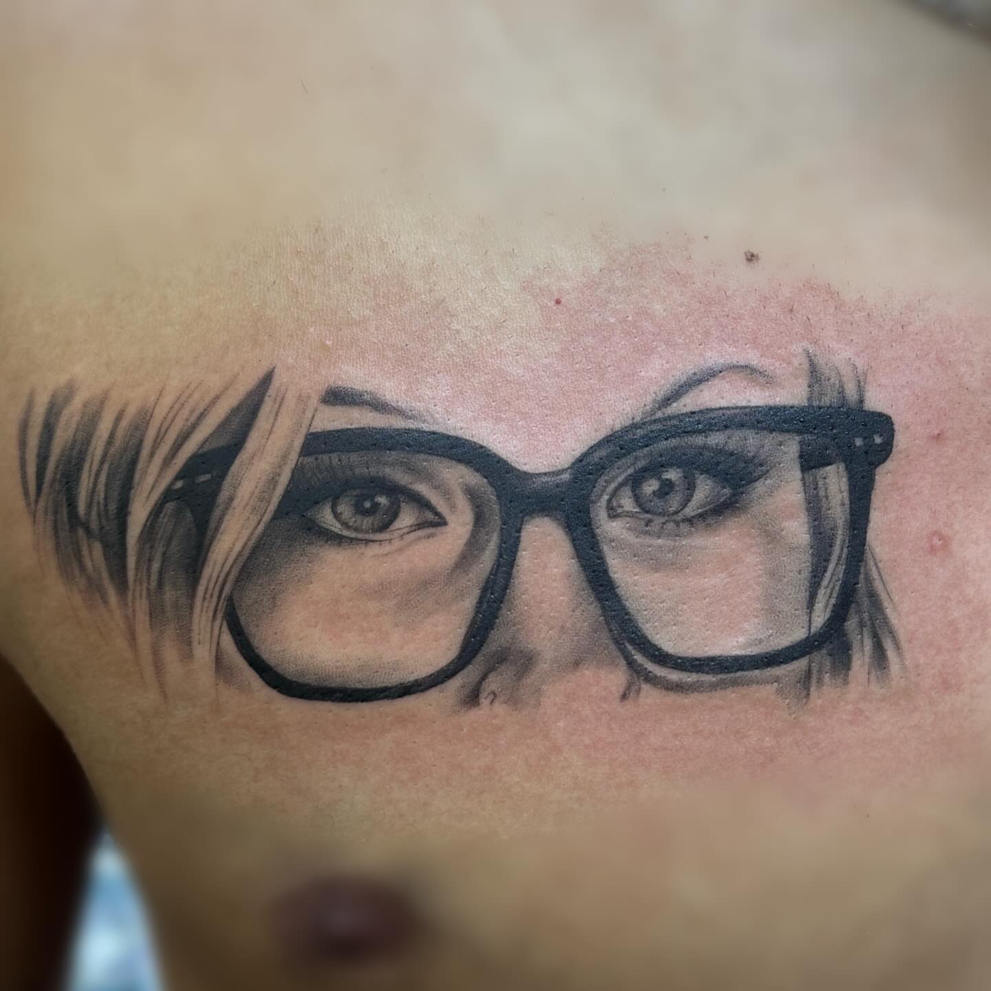 Eyeglasses realism tattoo on the chest by Elly Bordwell