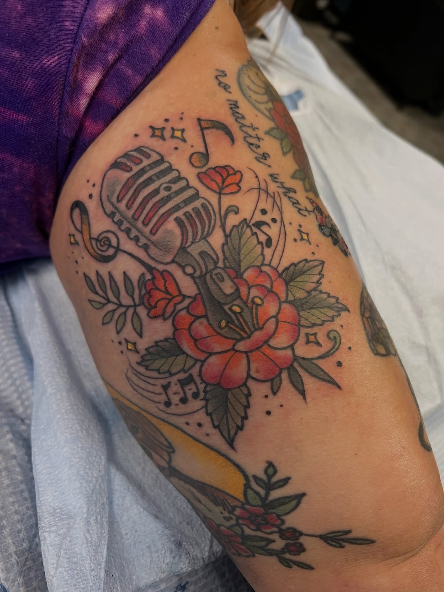 Microphone and floral bouquet American traditional tattoo on the upper arm by Corey Thompson, Butler, Pennsylvania