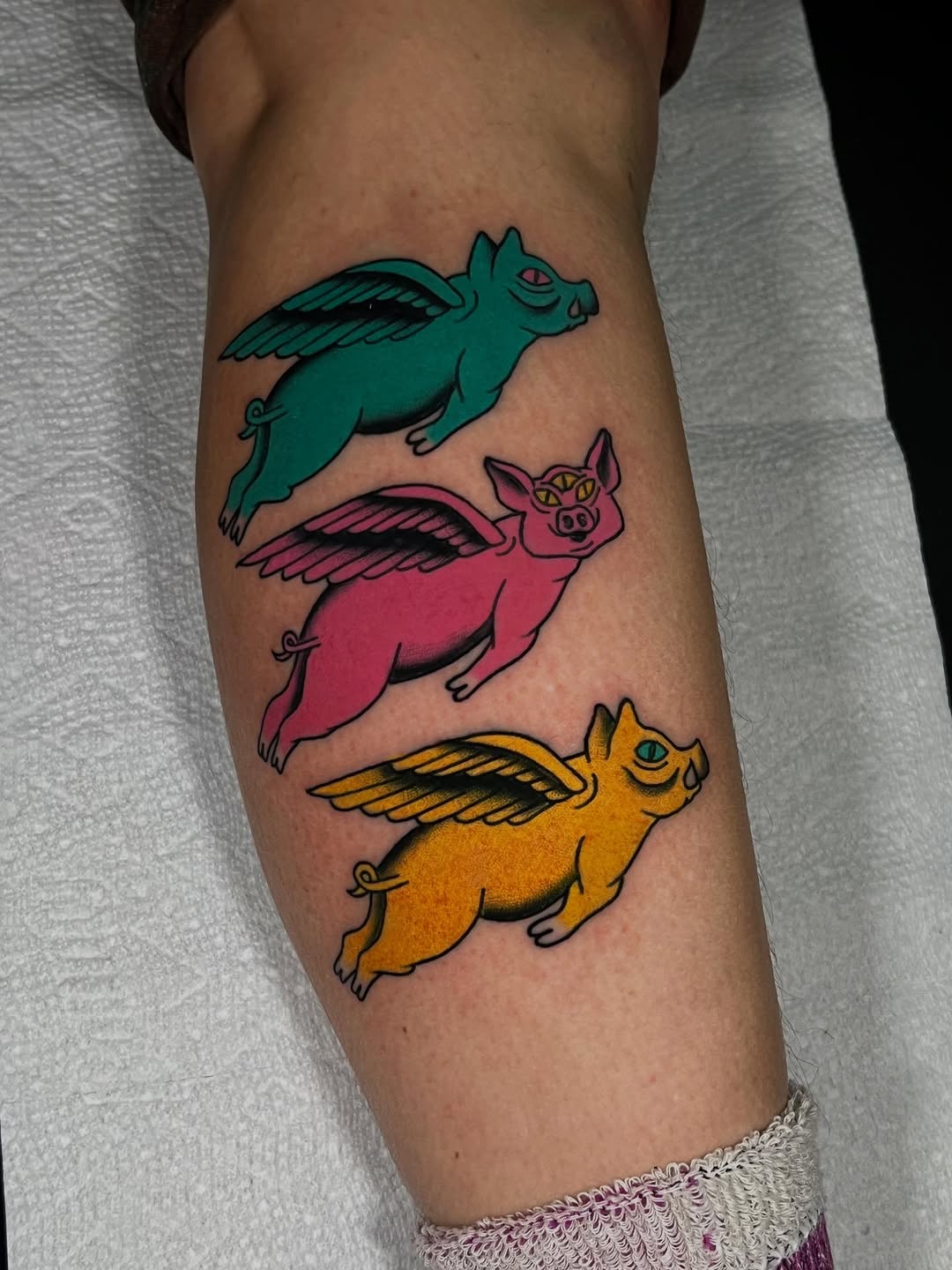 Three flying pigs American traditional tattoo on the forearm by {{Theo Glanton}}