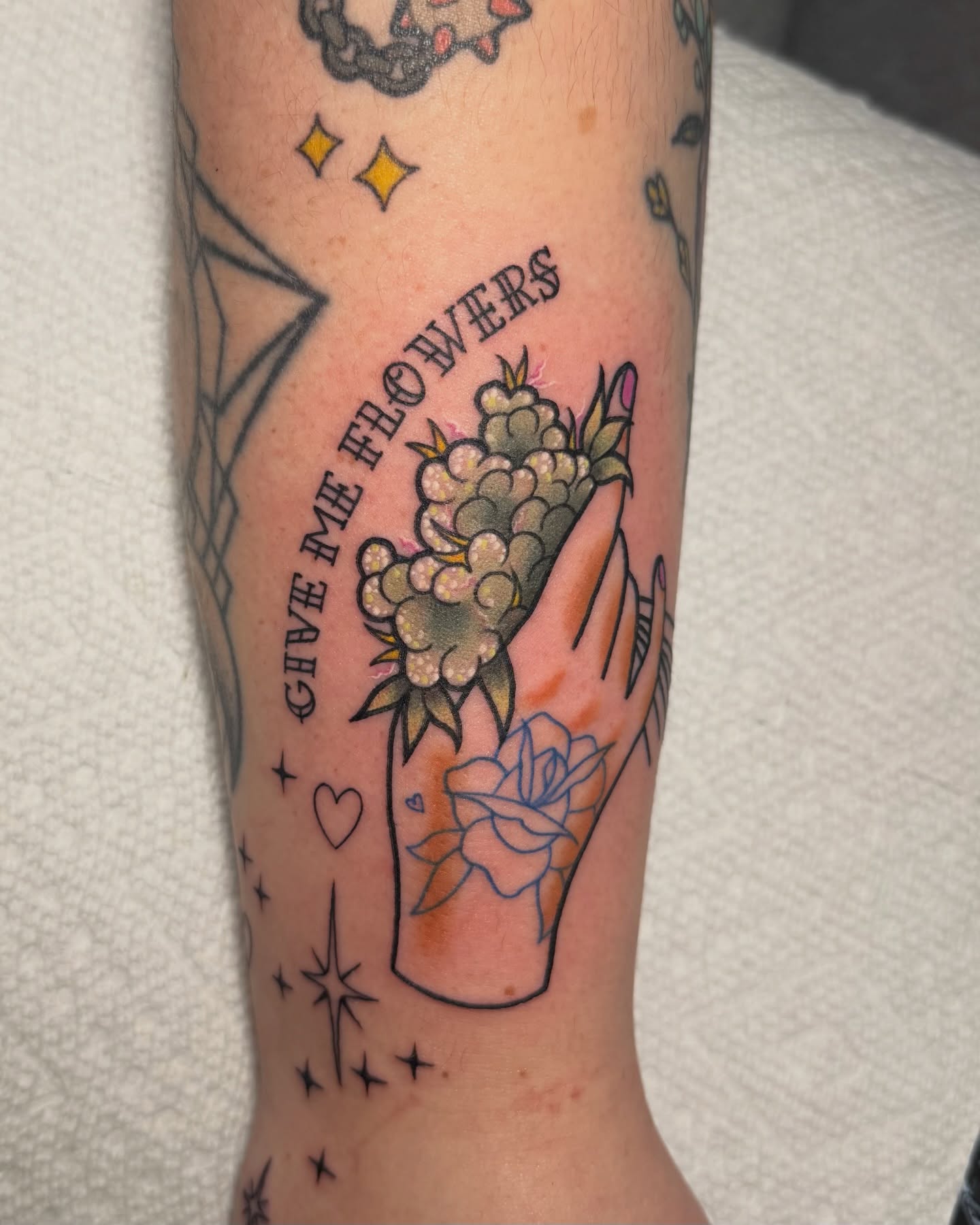 Flowers and hand American traditional tattoo on the forearm by Lyndze Masters