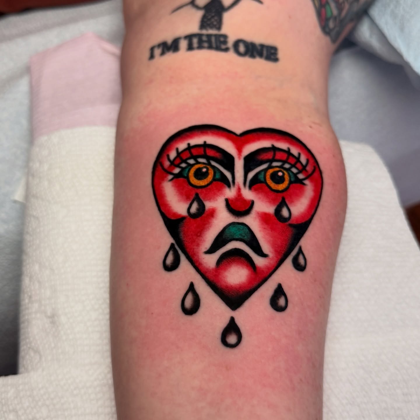 Heart with crying face American traditional tattoo on the forearm by Stevie Lowenstein, Cincinnati, Ohio