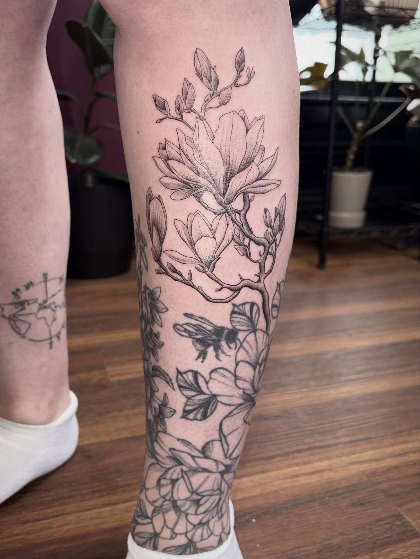 Magnolia blossoms and bee black and grey tattoo on the calf by Kelli Donegan ๐ท