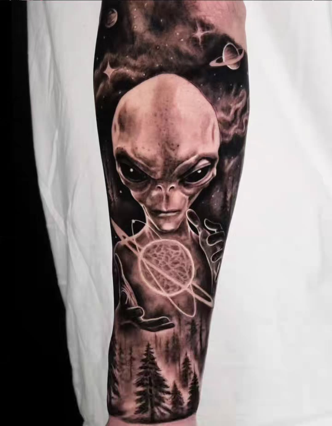 Alien in space with forest surrealism tattoo on the forearm by Brandon Rabago, Fort Worth, Texas
