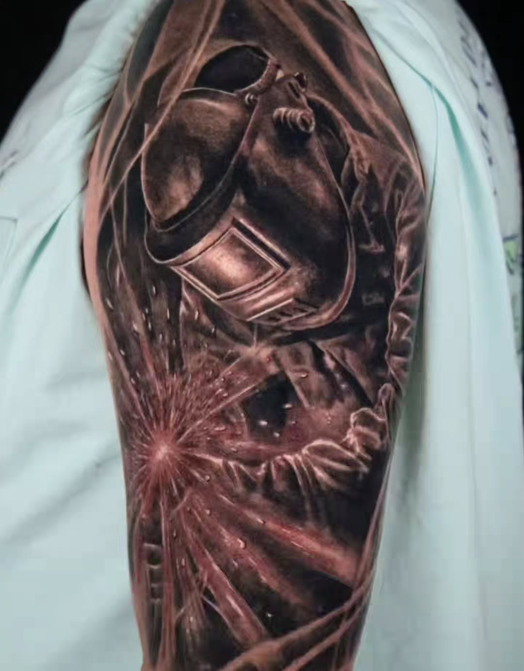 Welder with sparks realism tattoo on the upper arm by Brandon Rabago, Fort Worth, Texas