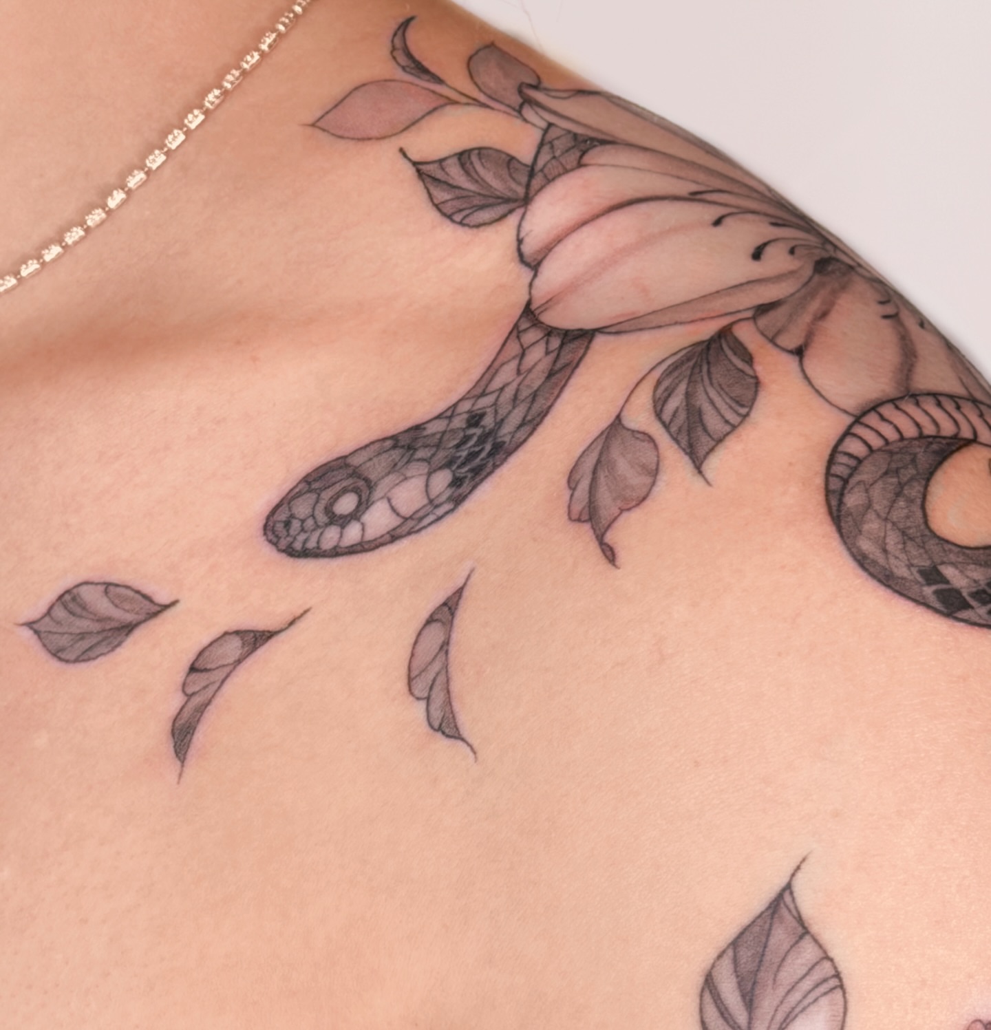 Snake and leaves black and grey tattoo on the shoulder by Charlotte