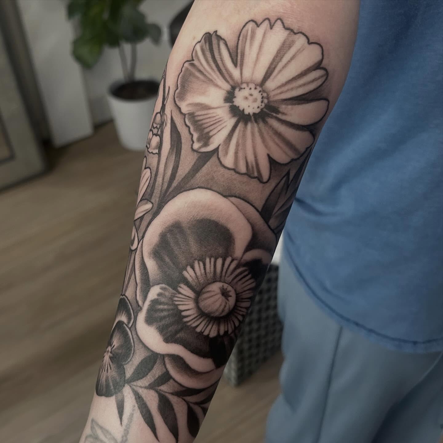 Floral arrangement black and grey tattoo on the forearm by Whitney Harbin