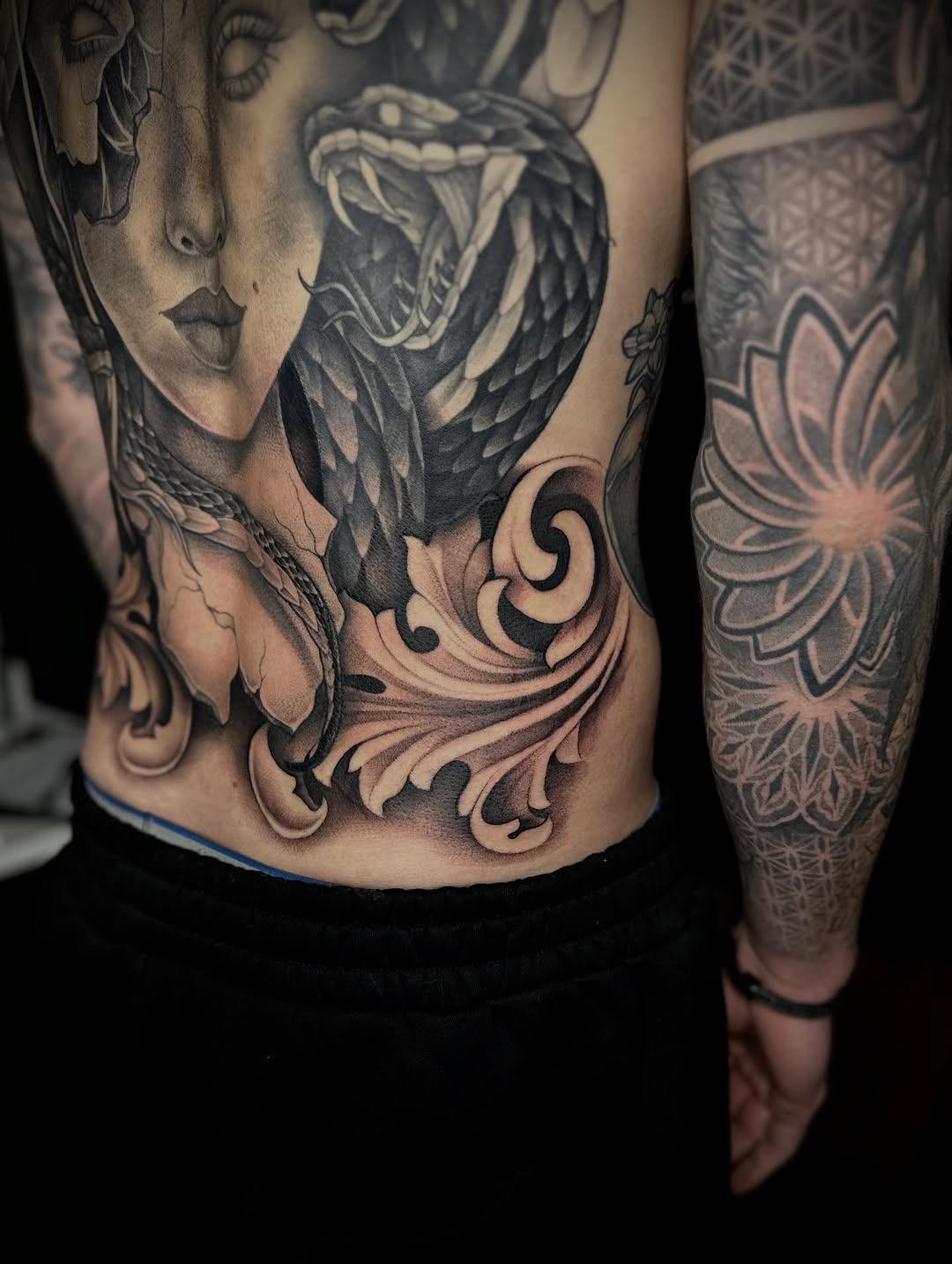Woman and snake with ornamental elements realism tattoo on the torso by Madison Orchard Tattoos