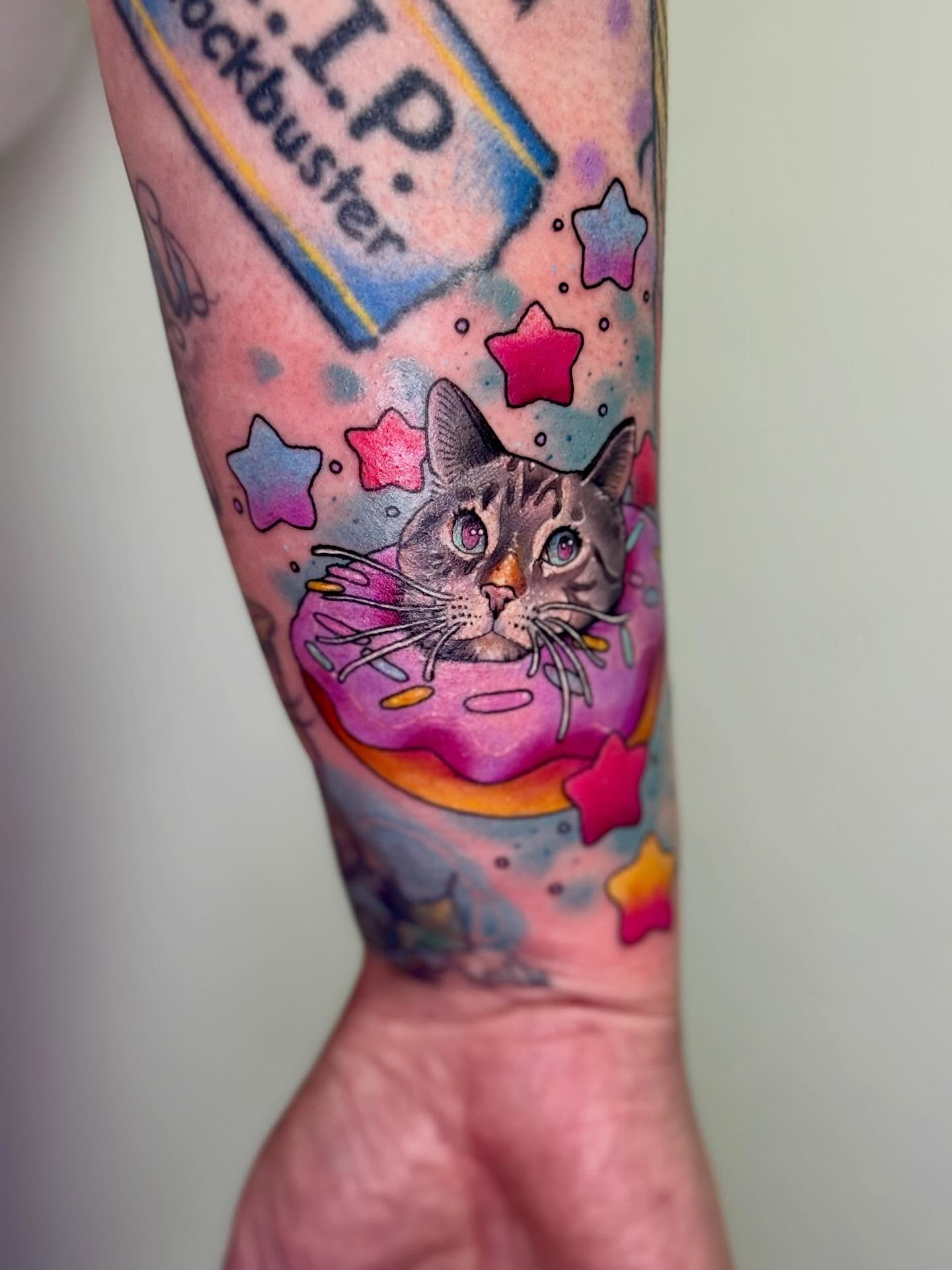 Cat with donut new school tattoo on the forearm by Eileen Joyce