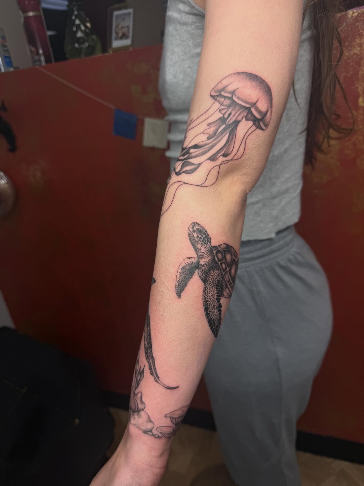 Jellyfish and turtle black and grey tattoo on the forearm by Imani