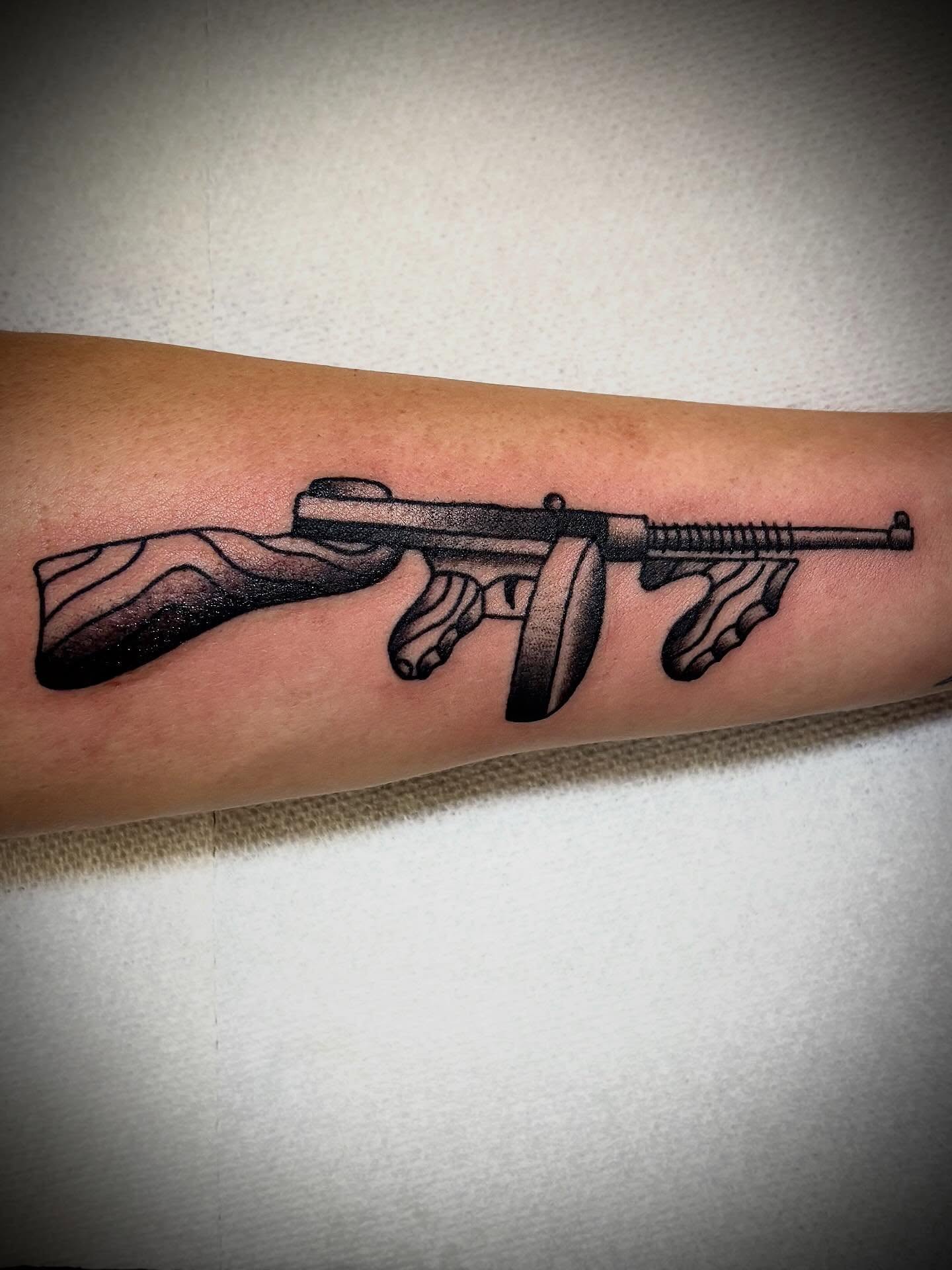 Machine gun black and grey tattoo on the forearm by JD Bassett