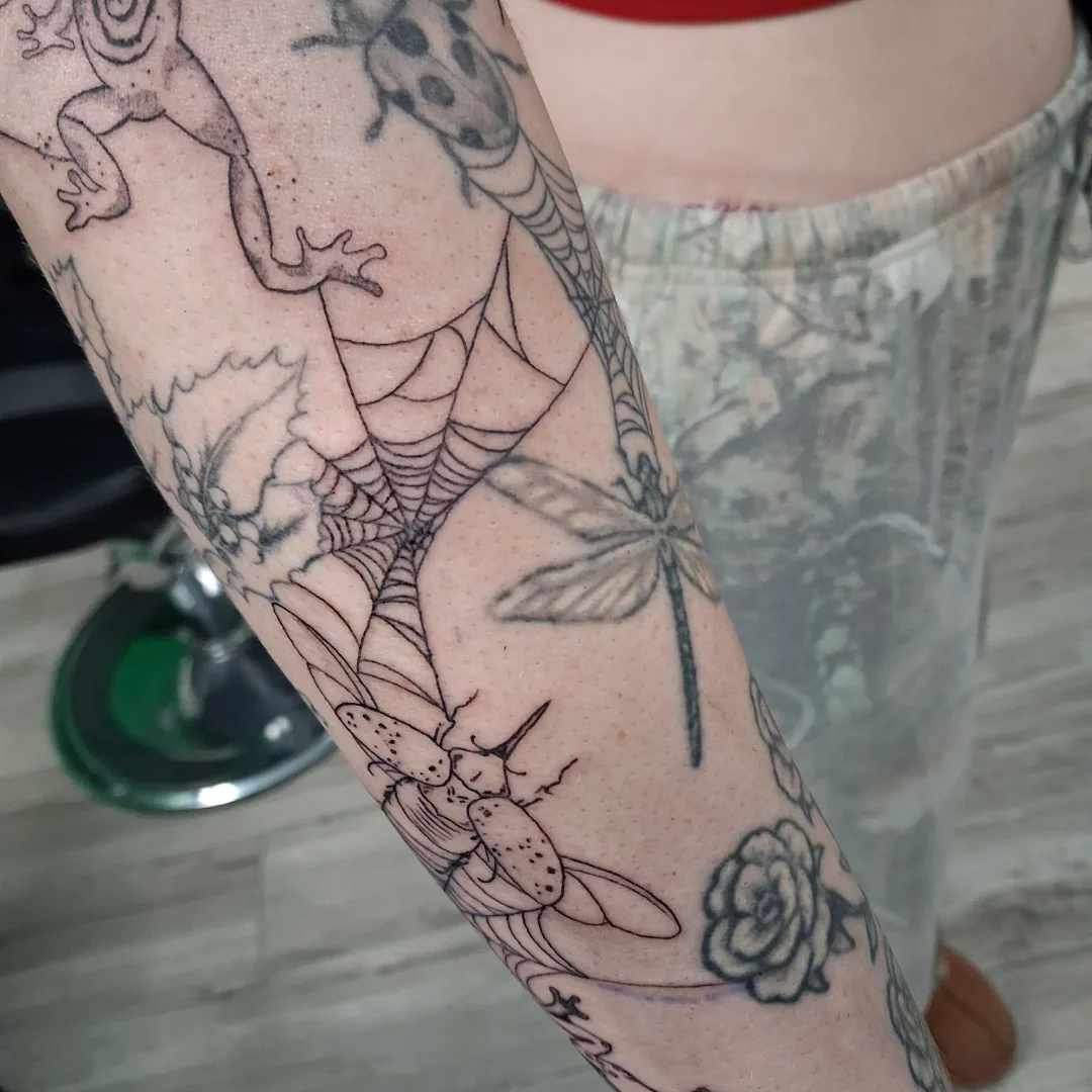 Insects and flowers black and grey tattoo on the forearm by James Ostler