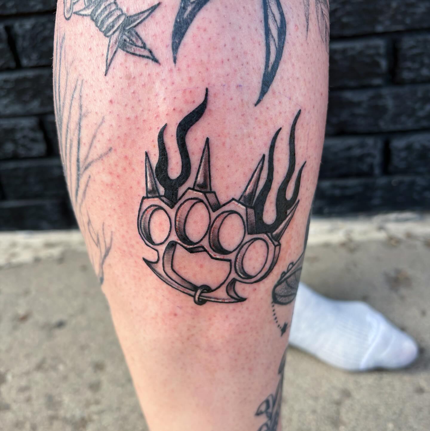 Brass knuckles black and grey tattoo on the forearm by Demi Flores 🖤