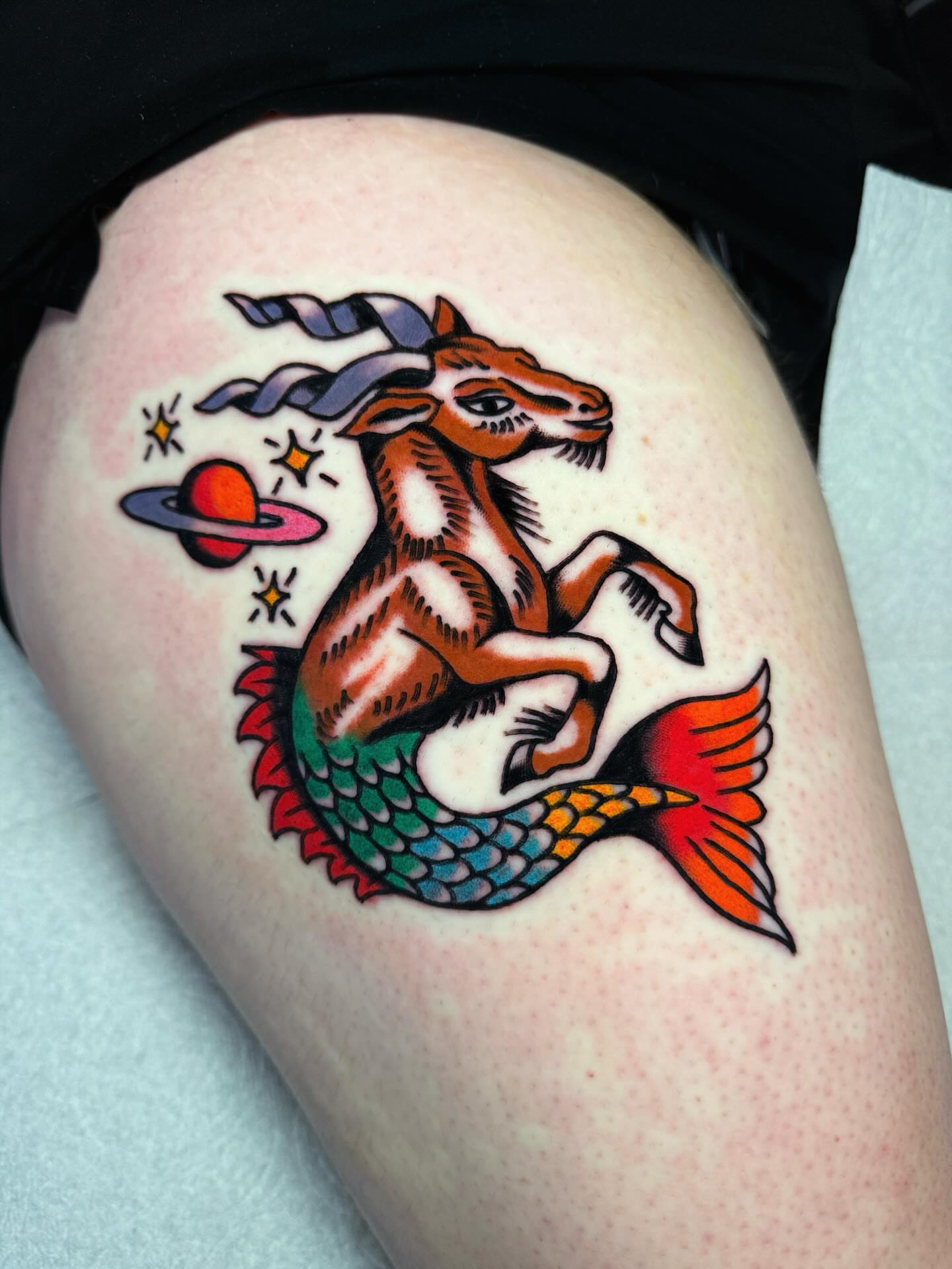 Goat and fish American traditional tattoo on the thigh by Britt Kuechenmeister, Culver City, California