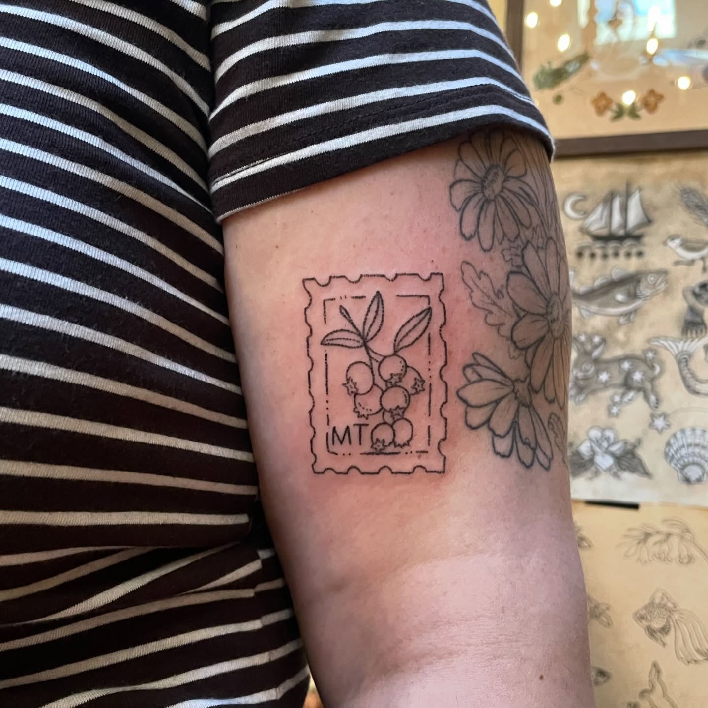 Postage stamp with berries black and grey tattoo on the forearm by Roe