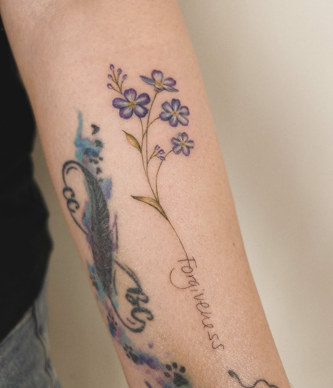 Forget-me-not flowers and script watercolor tattoo on the forearm by Helly March