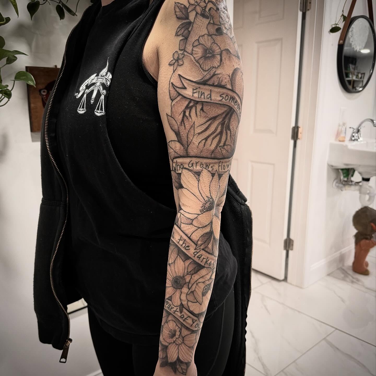 Flowers and banner black and grey tattoo on the forearm by Shannon Misitano