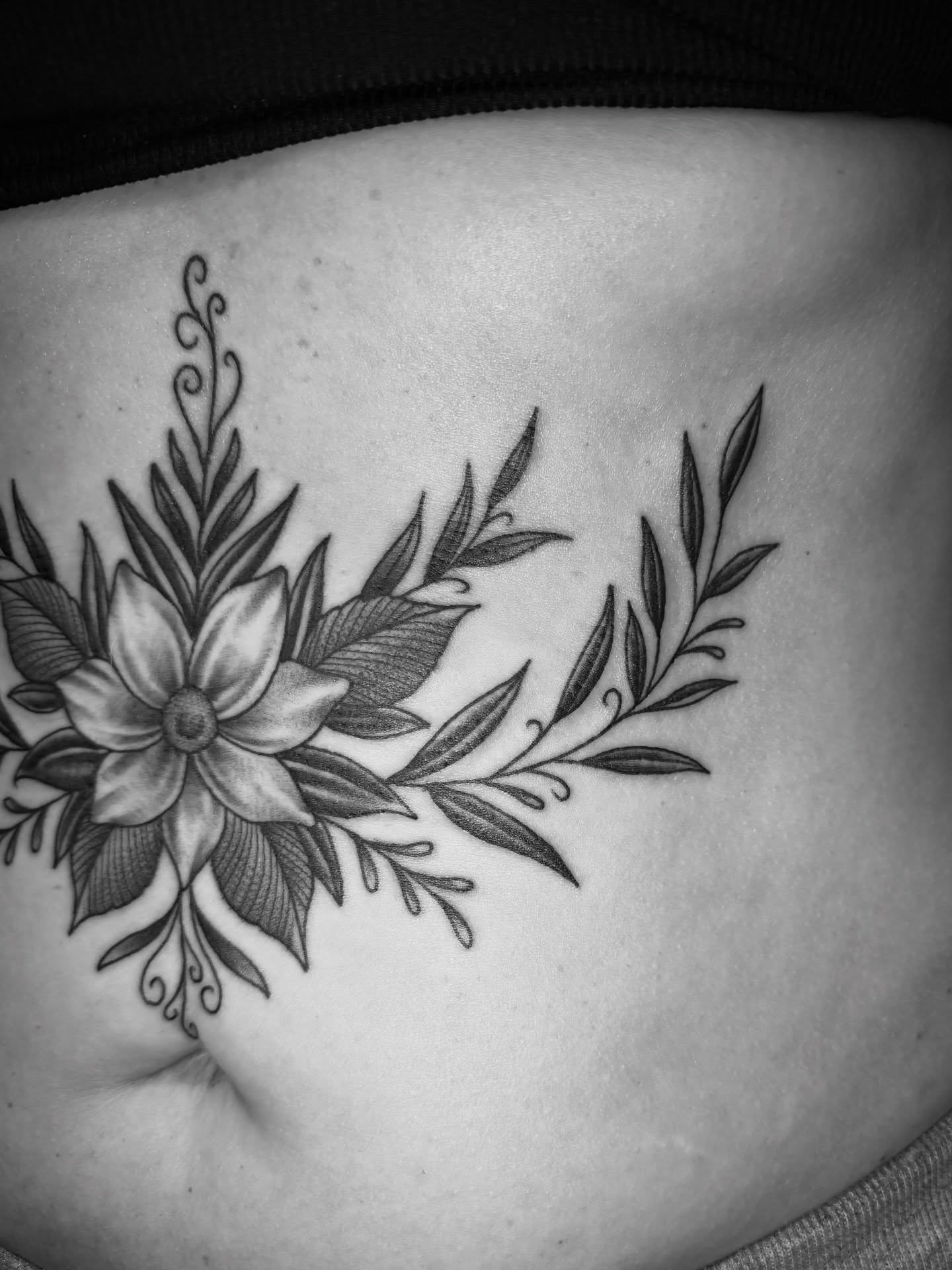 Flower and leaves black and grey tattoo on the ribs by Christopher Mikesell
