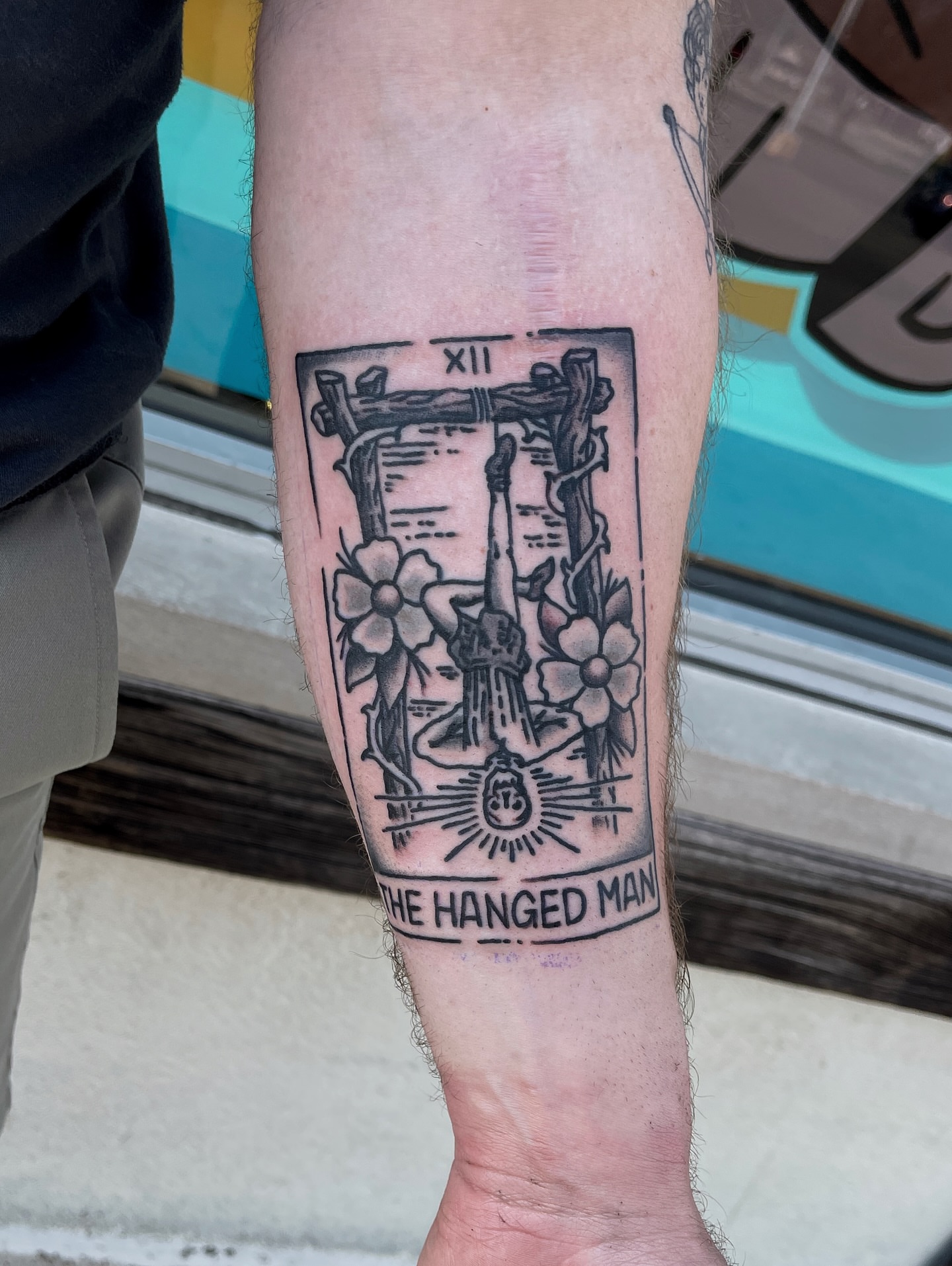 The hanged man tarot card black and grey tattoo on the forearm by Patrick Miller, Huber Heights, Ohio