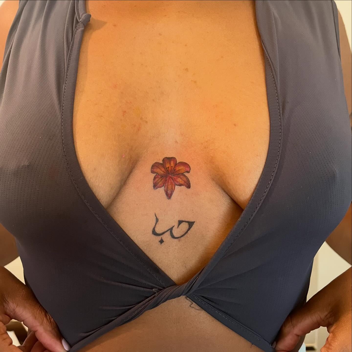 Flower and Arabic script dotwork tattoo on the chest by ren