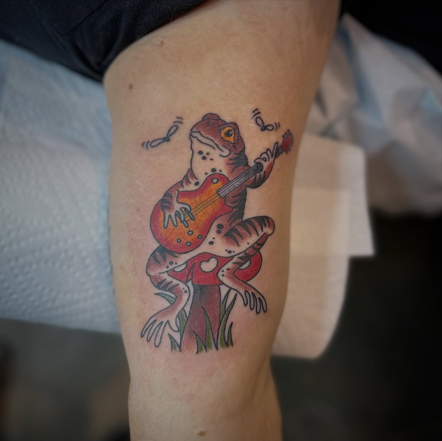 Frog playing guitar American traditional tattoo on the thigh by Walk-in American Traditional Tattoos Las
