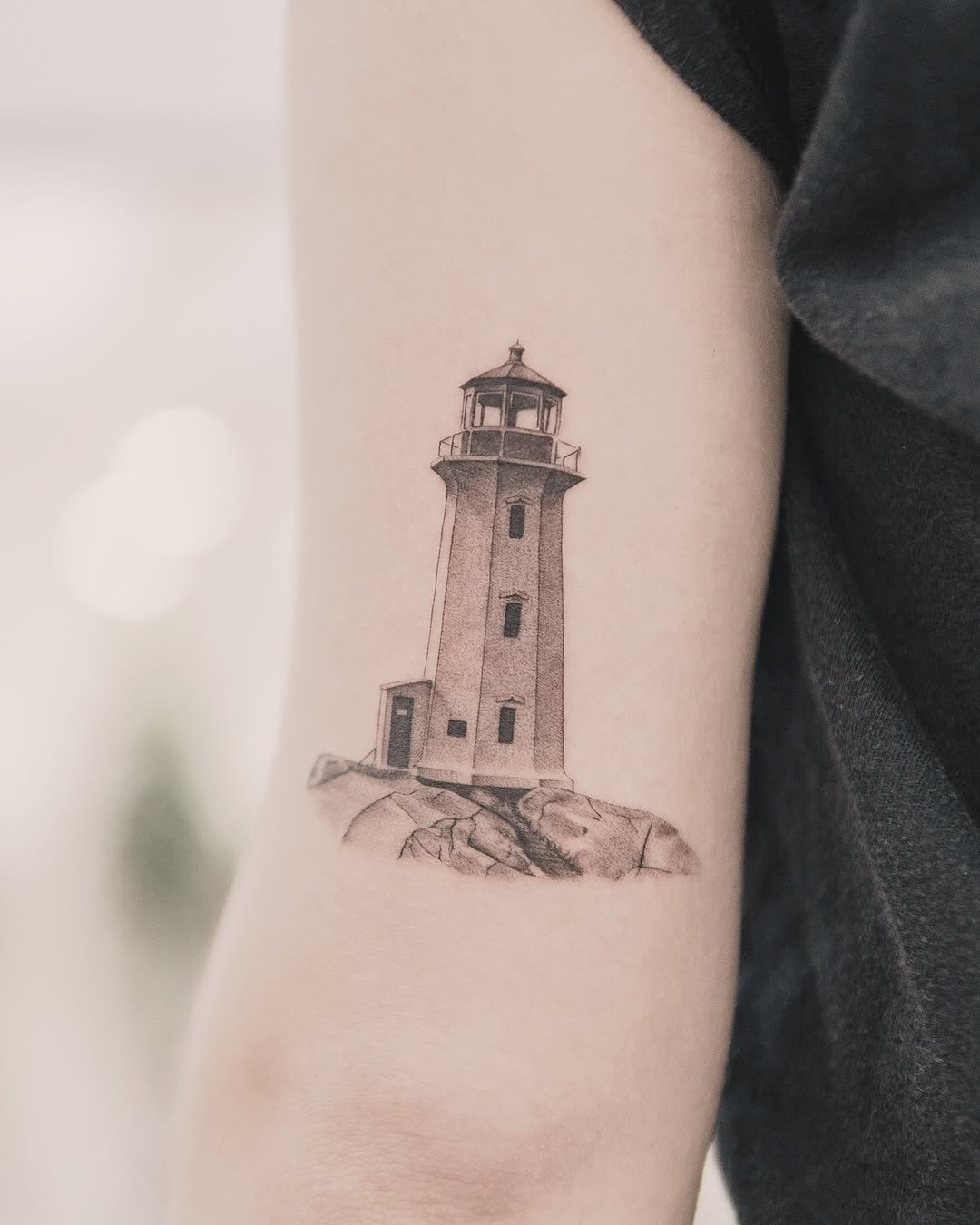 Lighthouse on rocks minimalist tattoo on the forearm by Joey