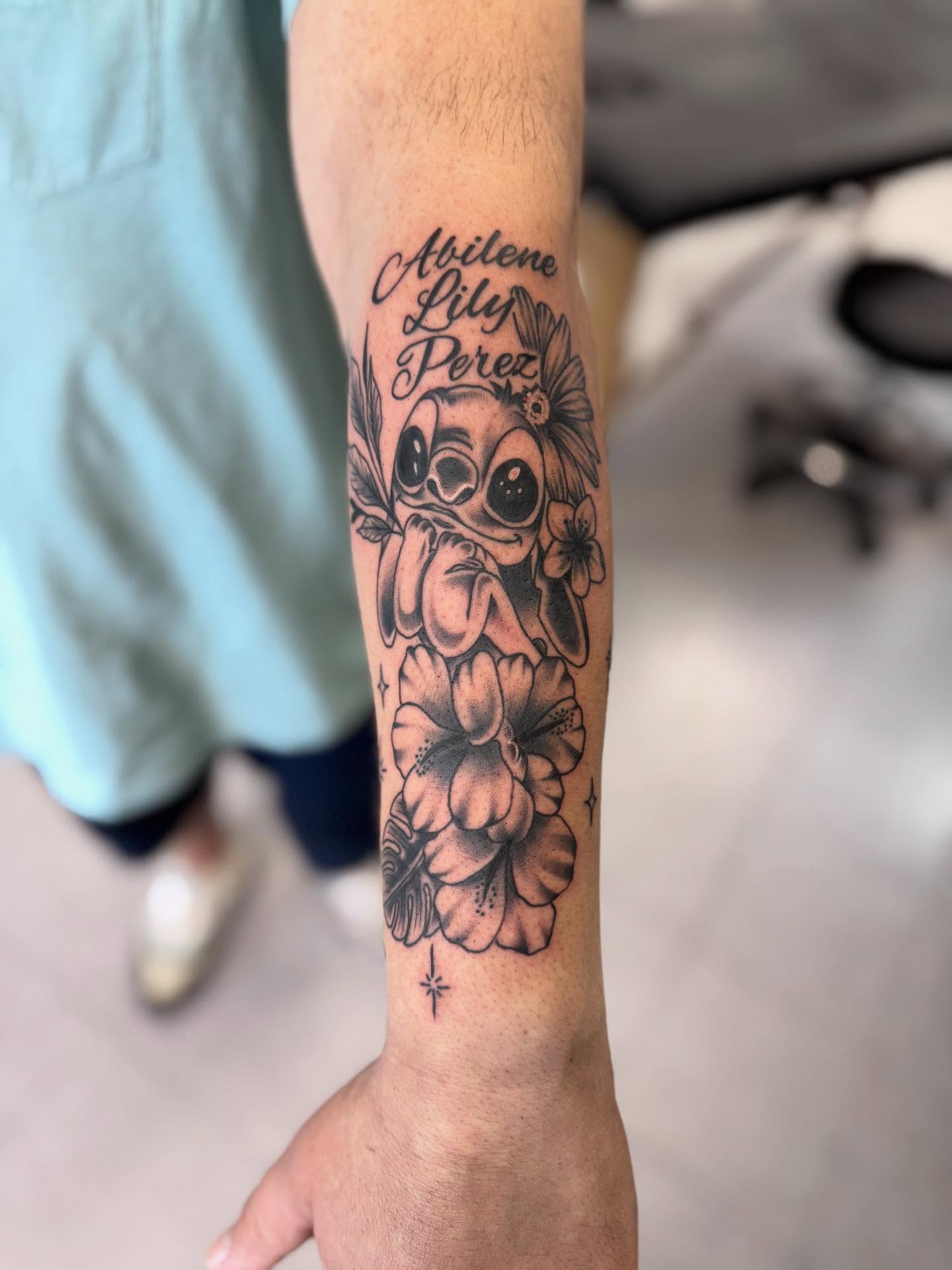 Lilo and Stitch black and grey tattoo on the forearm by Jacob - Tattoo Artist