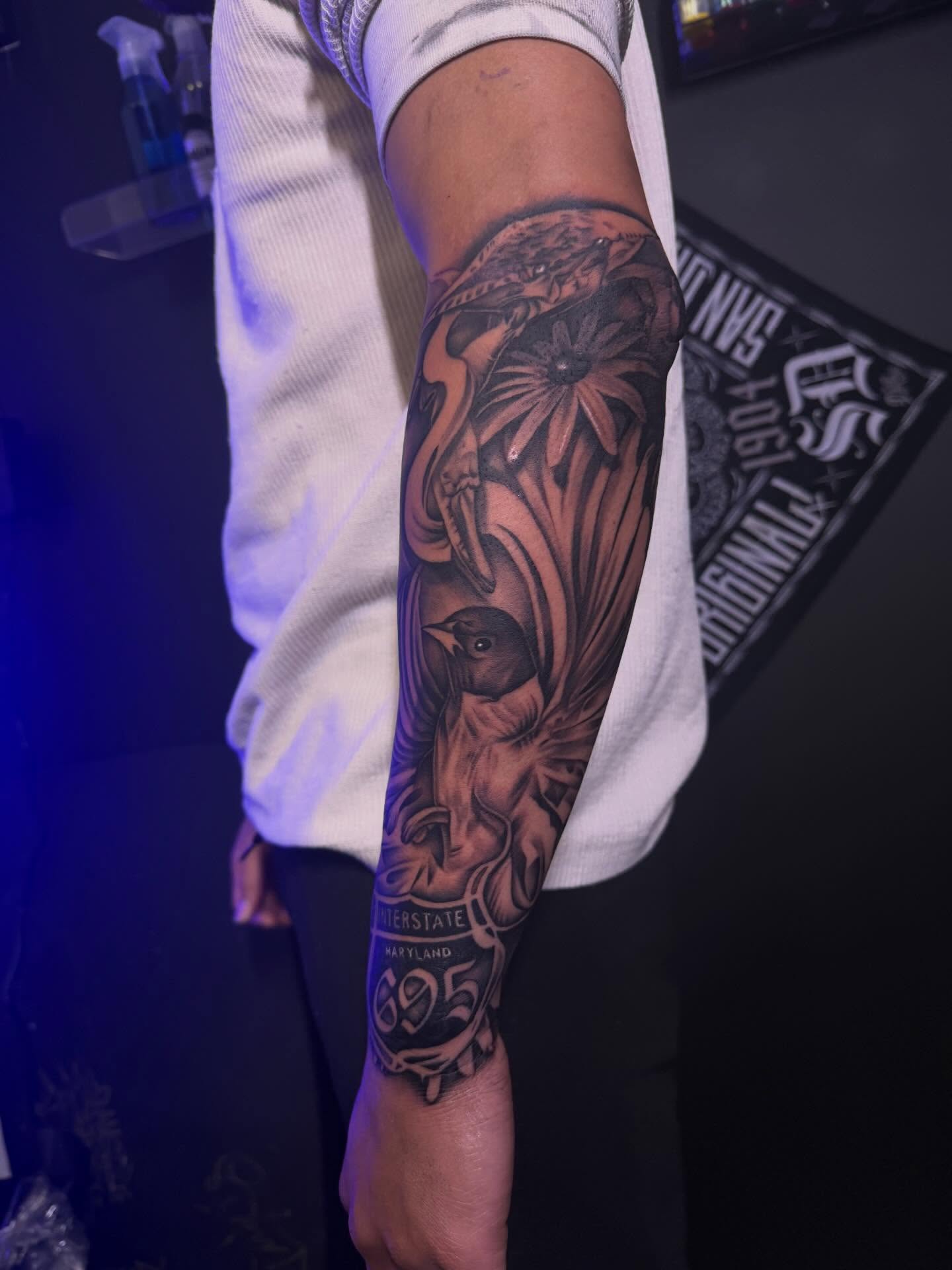 Bird and palm tree realism tattoo on the forearm by San Diego Tattoo Artist