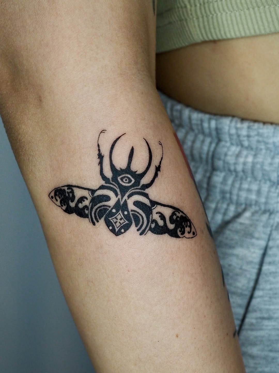 Stylized beetle with eye fine line tattoo on the forearm by A. Eye Tat