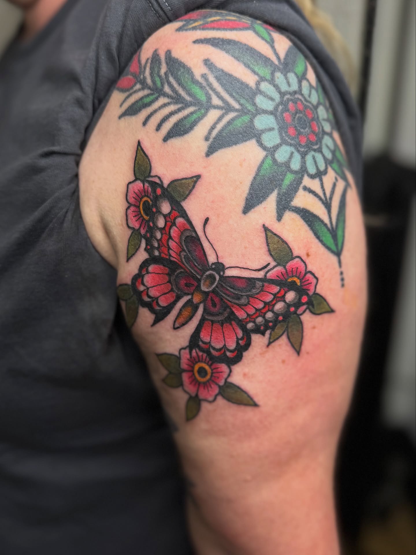 Butterfly and flowers American traditional tattoo on the shoulder by Chloe Marie