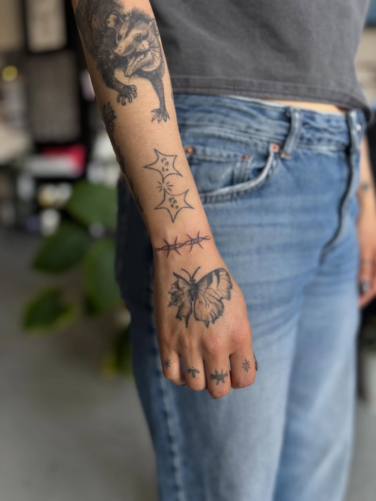 Badger, stars, barbed wire, butterfly, bees black and grey tattoo on the forearm by Marissa Whitaker