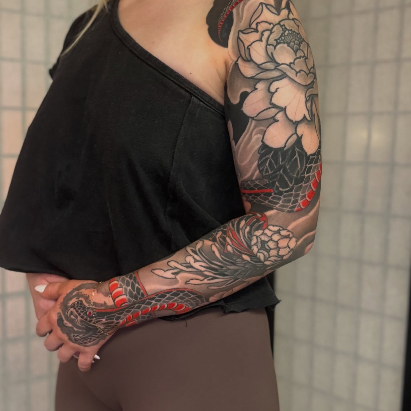Snake and peony American traditional tattoo on the upper arm by Dylan