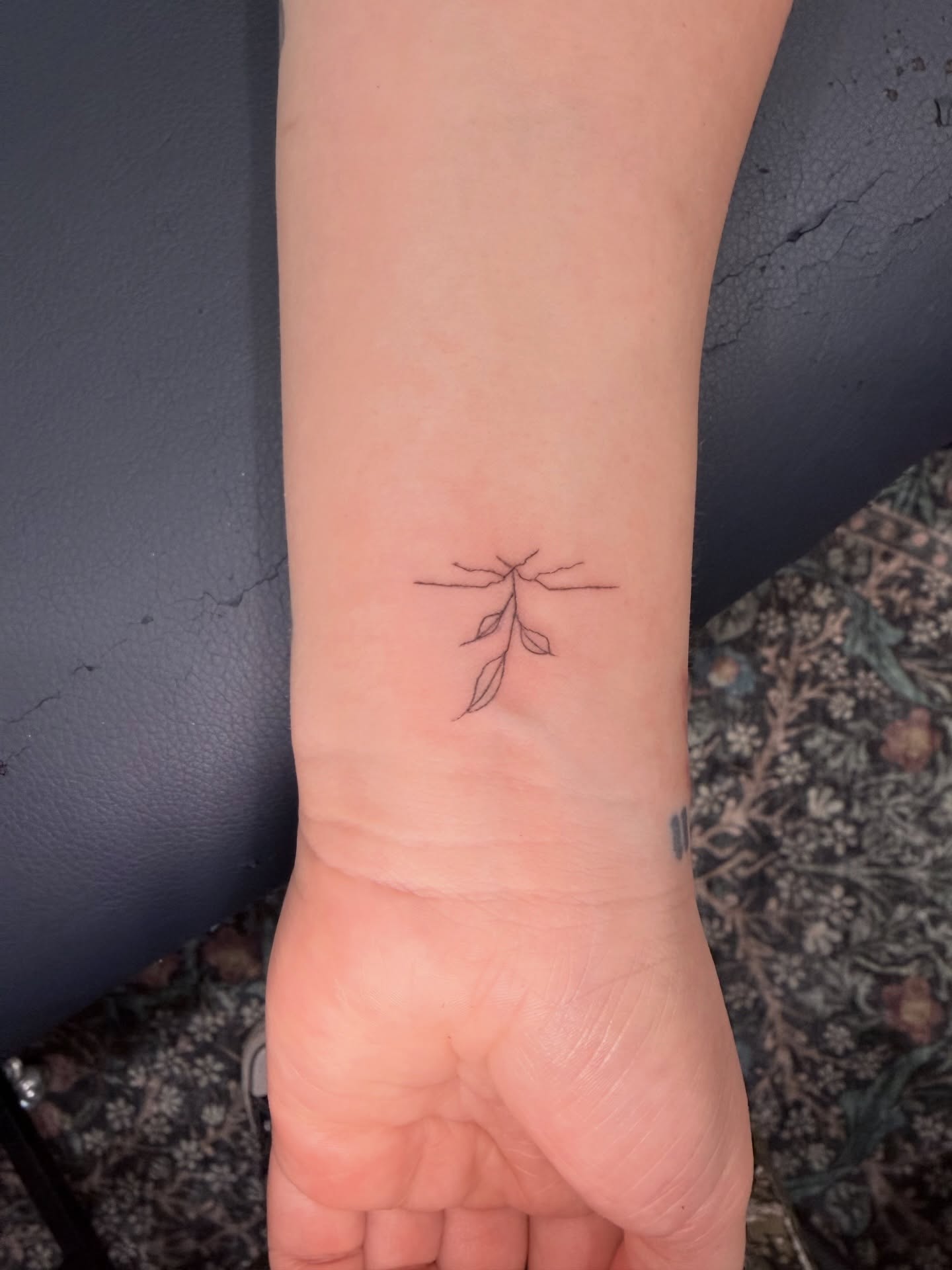 Branch with leaves fine line tattoo on the forearm by Reverie Studio