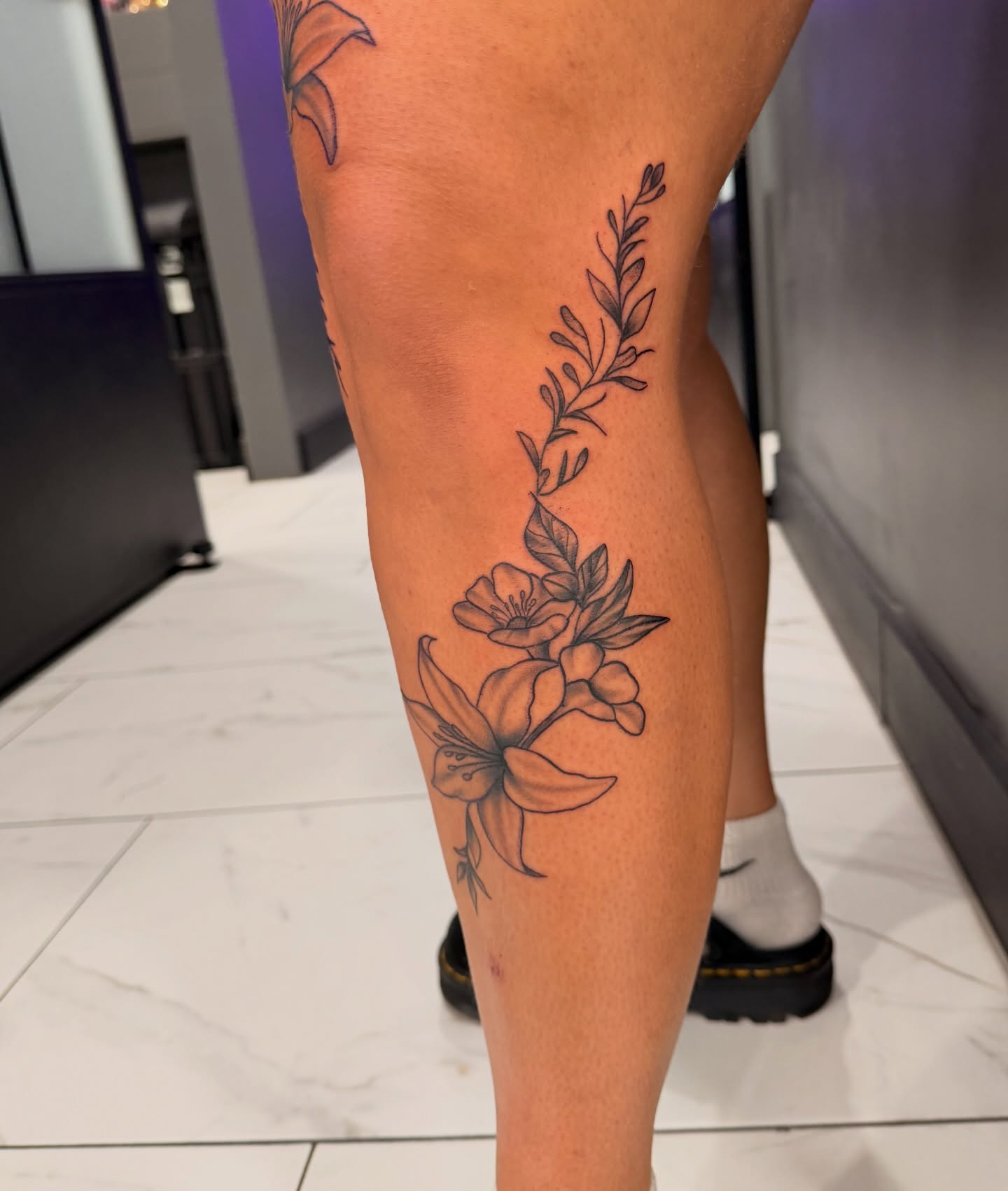 Floral arrangement black and grey tattoo on the calf by Lexi Odam