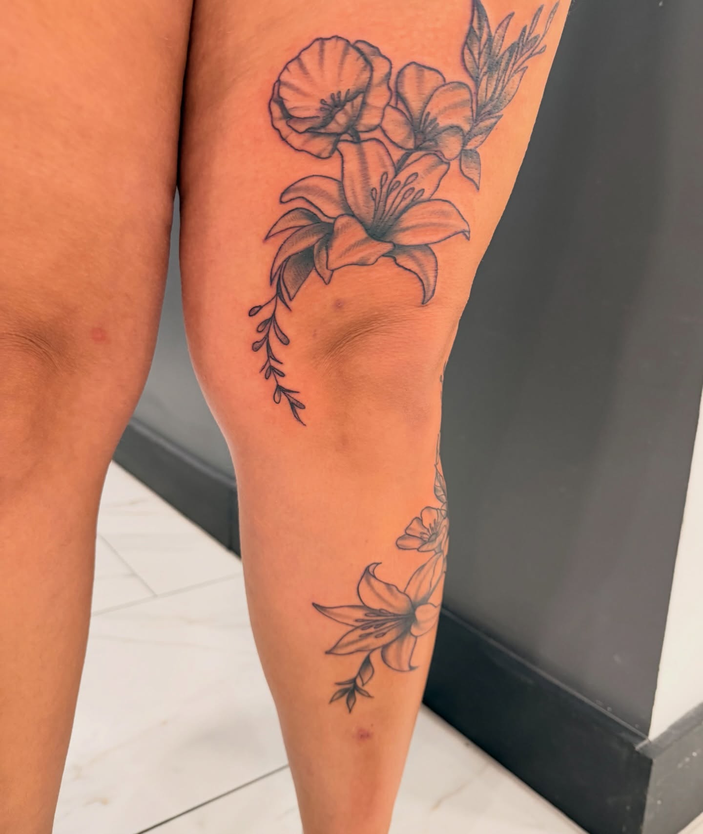 Lilies and poppies black and grey tattoo on the calf by Lexi Odam