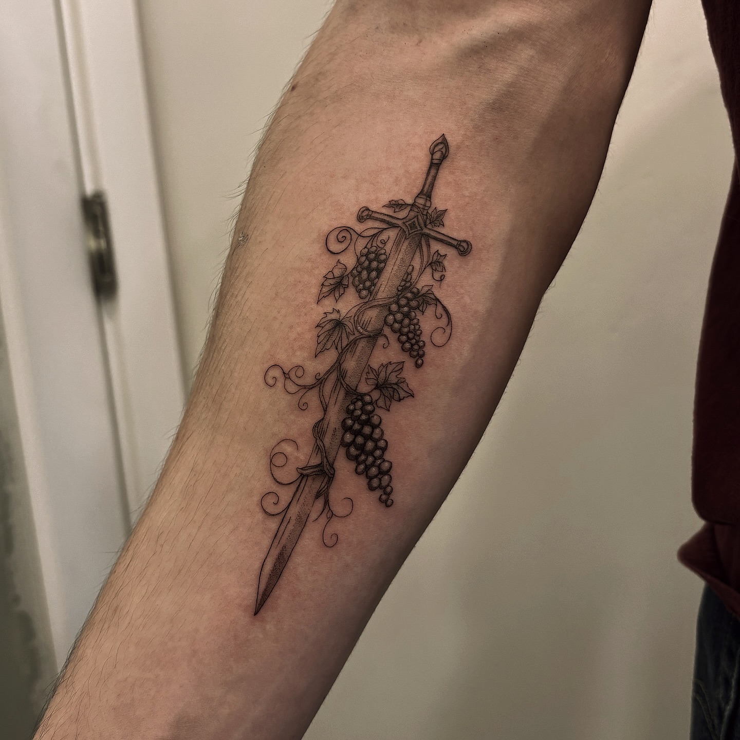 Sword and grapes black and grey tattoo on the forearm by Tayler, Tooele, Utah