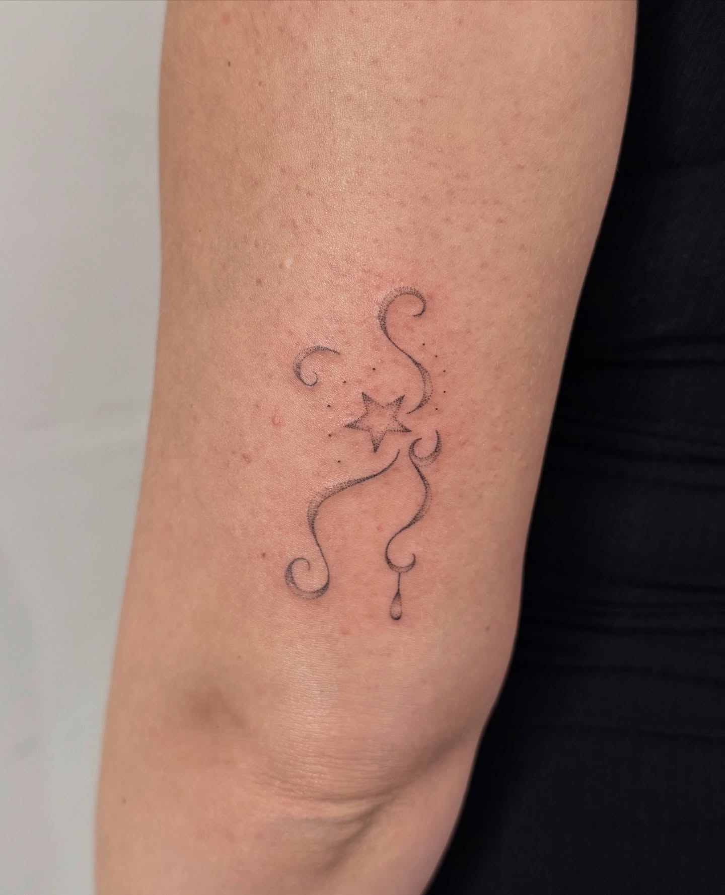 Star with swirls fine line tattoo on the forearm by Soomin